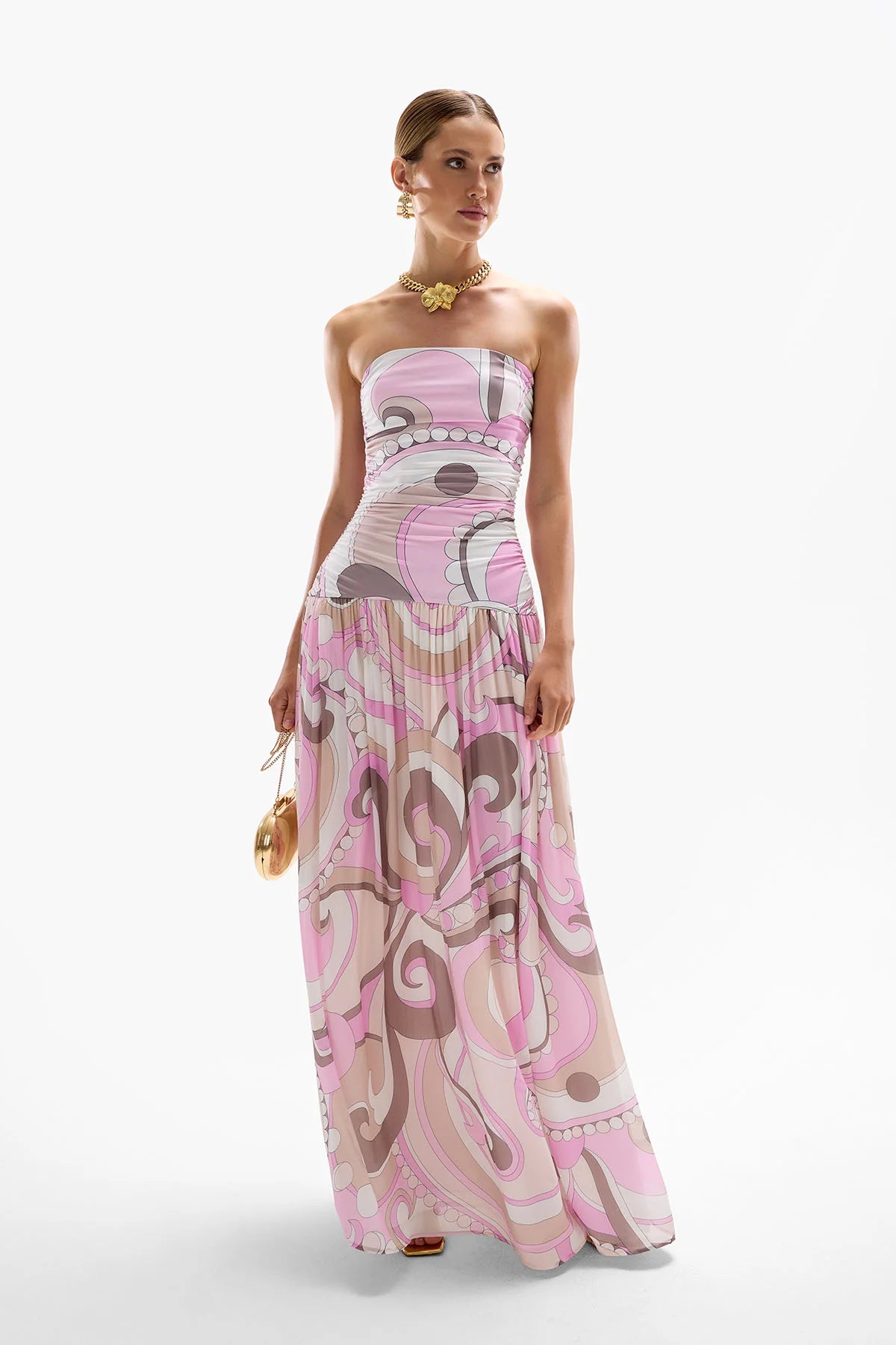 The Antibes Maxi Dress showcases a sophisticated drop-waist silhouette enhanced by subtle ruching along the side seams, creating a flattering, elegant fit. Its Dolce Pink palette blends cool berry tones with deep browns in fluid, swirling patterns that capture the essence of a vibrant seventies jet set aesthetic. Perfect for making a stylish statement, this dress combines timeless design with contemporary flair for a standout look.