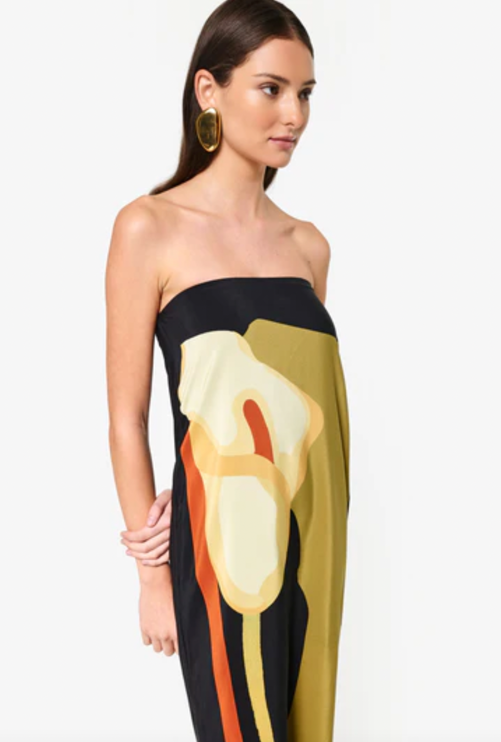 The Dalva Dress offers an elegant blend of sophistication and comfort with its strapless, column silhouette crafted from luxurious silk. Lined with the exclusive 'Calla' print, it provides both style and a smooth fit. The added elastic ensures secure support, while the back slit enhances mobility and adds a subtle allure. An invisible zipper completes the design for a flawless finish, making it an ideal choice for any refined occasion. Designed by Laura Cangussu in collaboration with Couper.