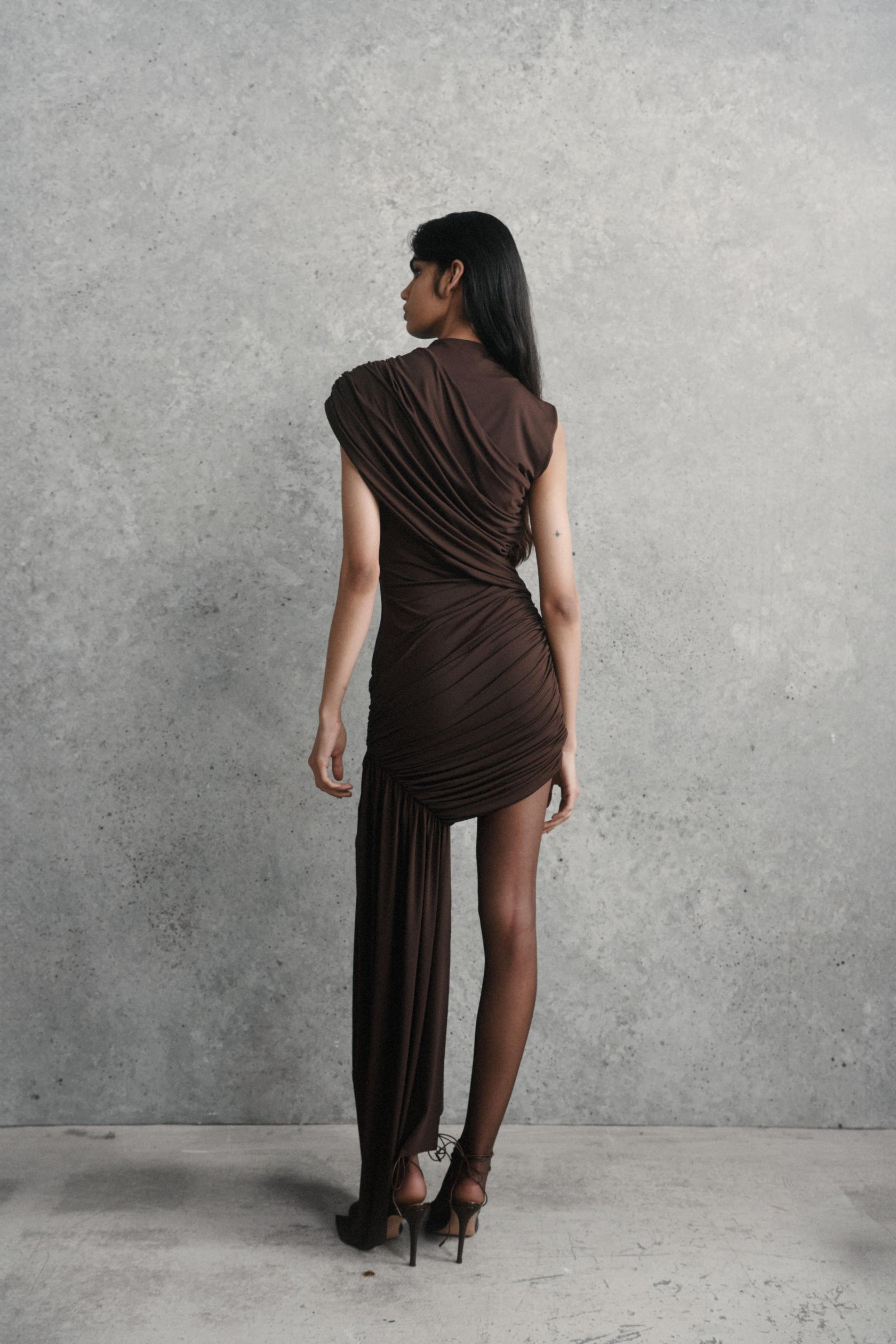 The Ravenna Mini Dress features a fully lined, lightweight jersey fabric that drapes elegantly for a smooth, delicate flow. Designed with a grown-on funnel neck and detailed draping across the shoulder and waist, it offers a modern silhouette with effortless style. The asymmetric sash on the skirt adds dramatic flair, while the structure allows for comfortable bra wear, making this dress both stylish and practical for contemporary occasions.