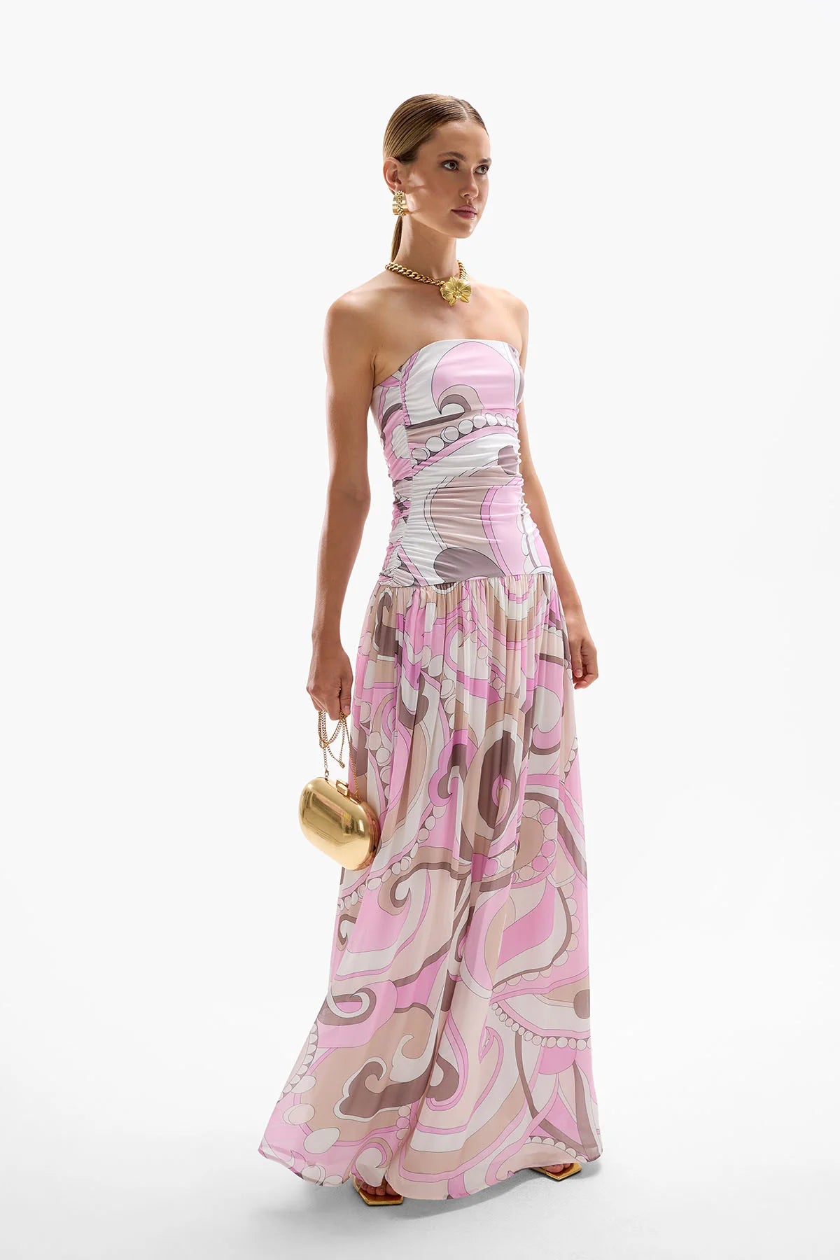 The Antibes Maxi Dress showcases a sophisticated drop-waist silhouette enhanced by subtle ruching along the side seams, creating a flattering, elegant fit. Its Dolce Pink palette blends cool berry tones with deep browns in fluid, swirling patterns that capture the essence of a vibrant seventies jet set aesthetic. Perfect for making a stylish statement, this dress combines timeless design with contemporary flair for a standout look.