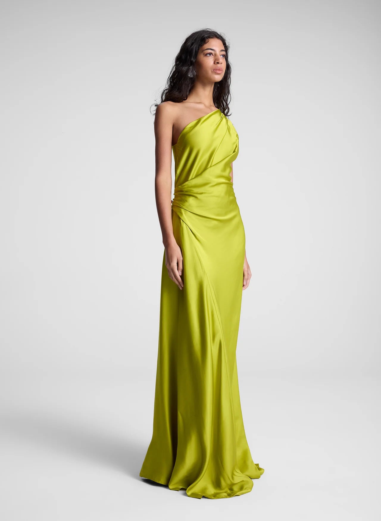 The Aster Satin One Shoulder Gown by A.L.C in radiant chartreuse is expertly crafted from fluid satin, delivering a graceful drape that enhances movement. Its one-shoulder design features delicate pleating at the shoulder and waist, sculpting a refined silhouette with architectural elegance. The asymmetrical cut accentuates the gown’s fluidity, making it a standout piece for sophisticated occasions.