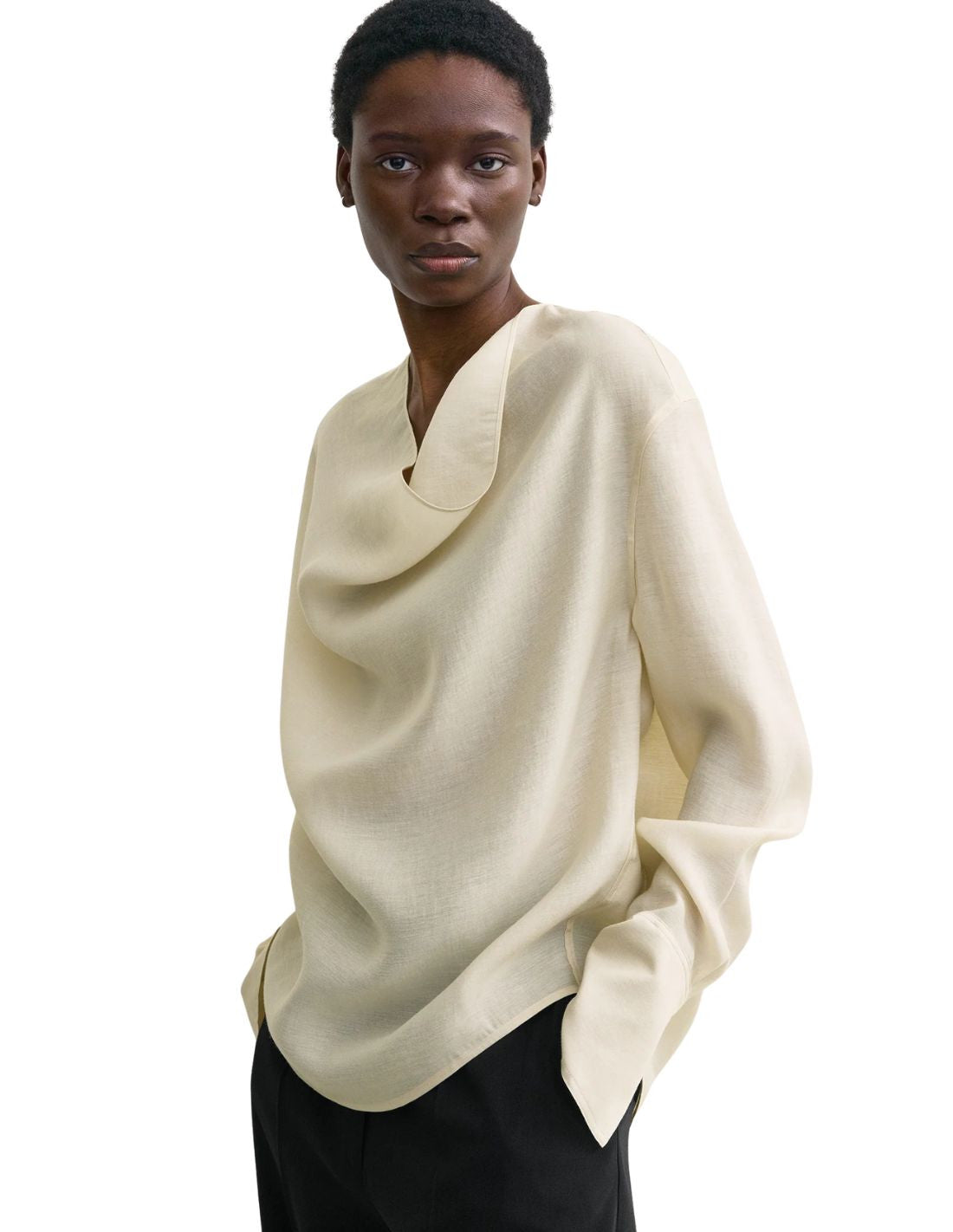 This TOTEME blouse combines refined craftsmanship with effortless style. Crafted from a luxurious blended wool in an elegant ecru shade, its oversized silhouette ensures comfort while maintaining a modern edge. The draped cowl neck creates a sophisticated focal point, complemented by long sleeves finished with buttoned cuffs for a polished look. The curved hem adds subtle fluidity, making this blouse a versatile piece that elevates both casual and formal ensembles with understated elegance.