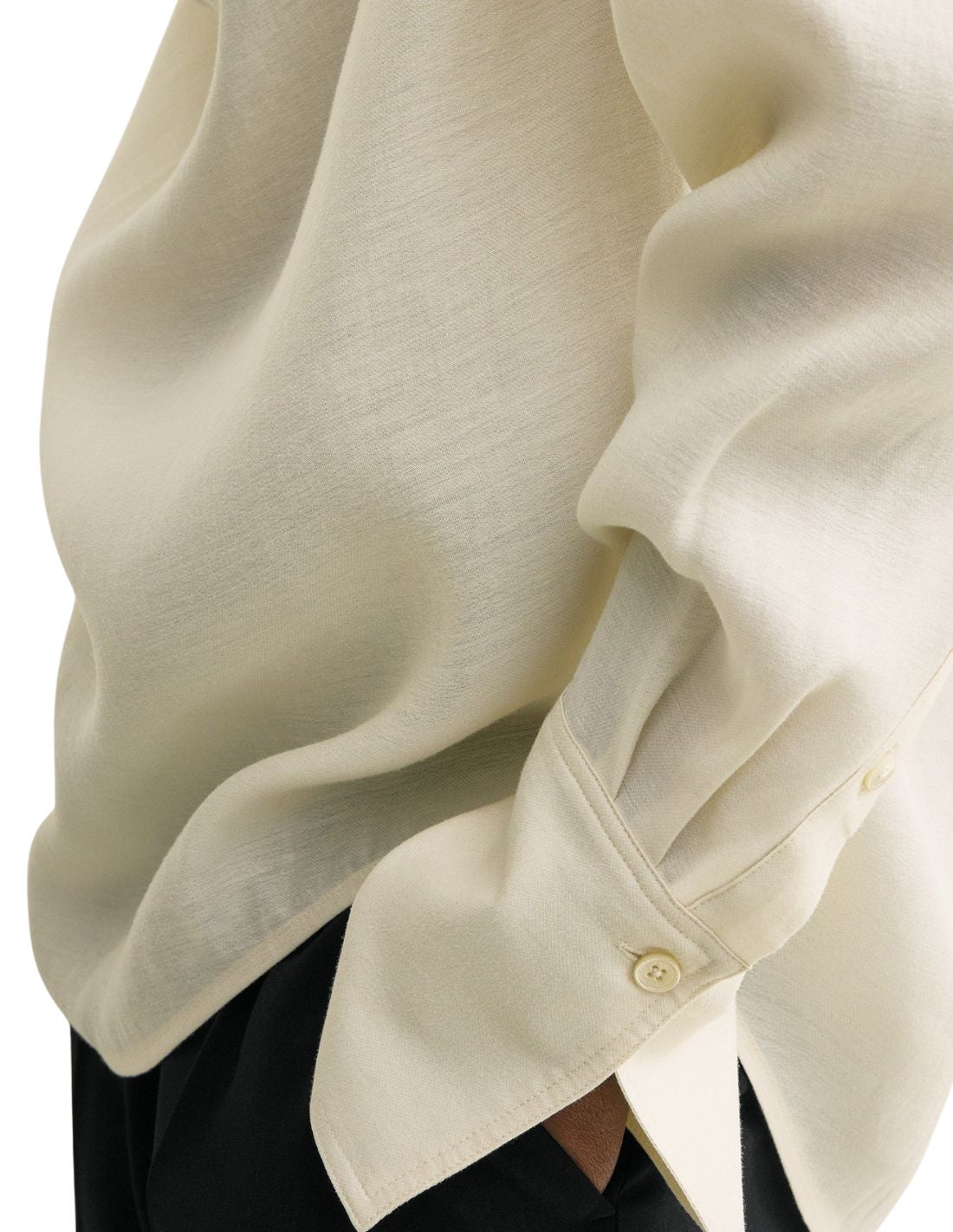 This TOTEME blouse combines refined craftsmanship with effortless style. Crafted from a luxurious blended wool in an elegant ecru shade, its oversized silhouette ensures comfort while maintaining a modern edge. The draped cowl neck creates a sophisticated focal point, complemented by long sleeves finished with buttoned cuffs for a polished look. The curved hem adds subtle fluidity, making this blouse a versatile piece that elevates both casual and formal ensembles with understated elegance.