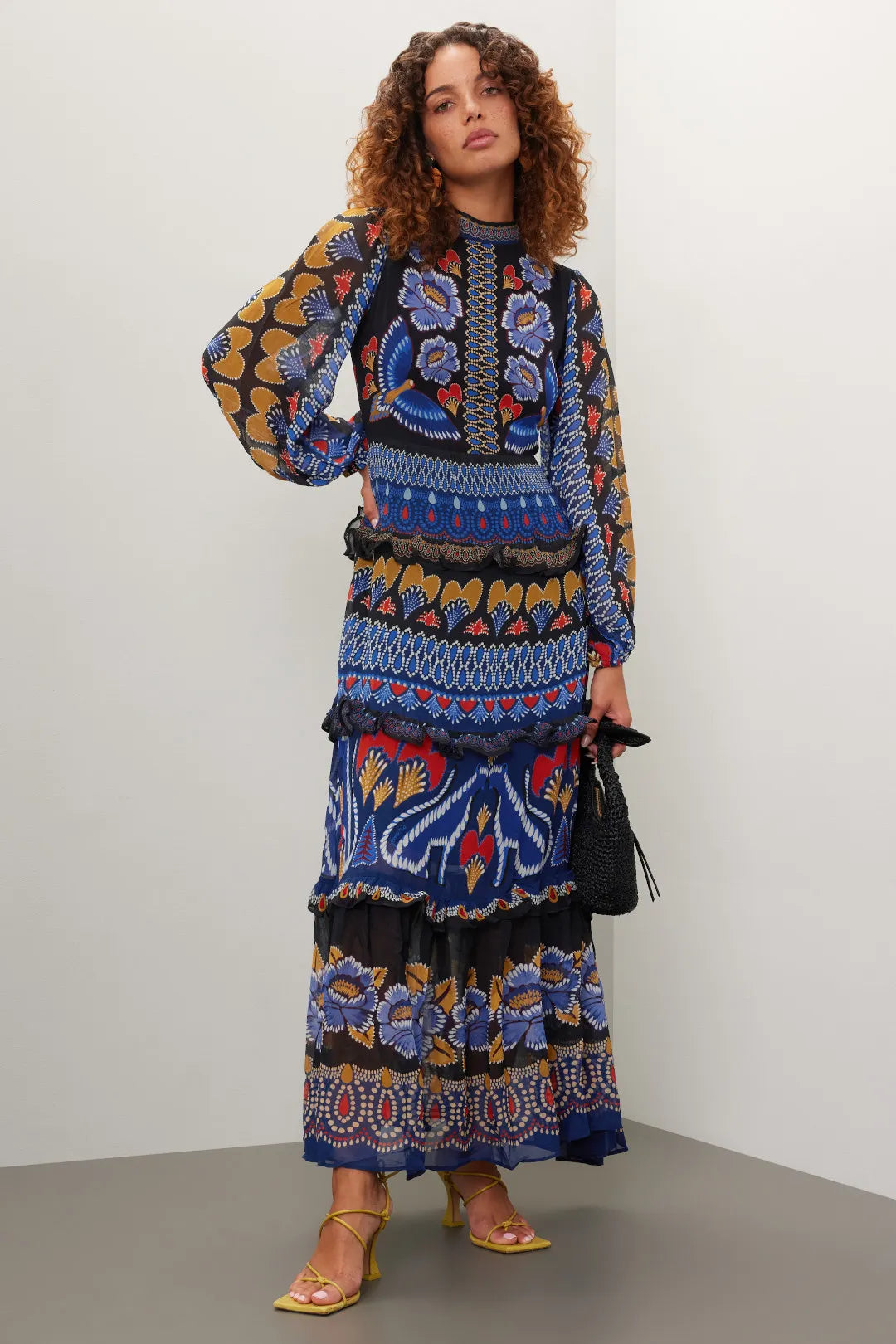 Brighten up fall with the Anika Maxi Dress from FARM Rio, featuring colorful contrasting prints and a charming ruffle trim. Made from lightweight black geometric print chiffon, this A-line dress flows elegantly with long sleeves and a stylish mock neck. The back zipper ensures a perfect fit, while the 56-inch length creates a dramatic silhouette. Perfect for those who want to capture summer's vibrant spirit all season long.