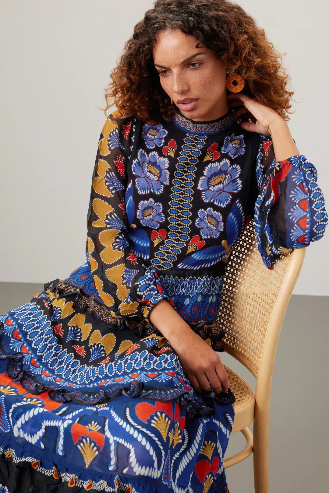 Brighten up fall with the Anika Maxi Dress from FARM Rio, featuring colorful contrasting prints and a charming ruffle trim. Made from lightweight black geometric print chiffon, this A-line dress flows elegantly with long sleeves and a stylish mock neck. The back zipper ensures a perfect fit, while the 56-inch length creates a dramatic silhouette. Perfect for those who want to capture summer's vibrant spirit all season long.