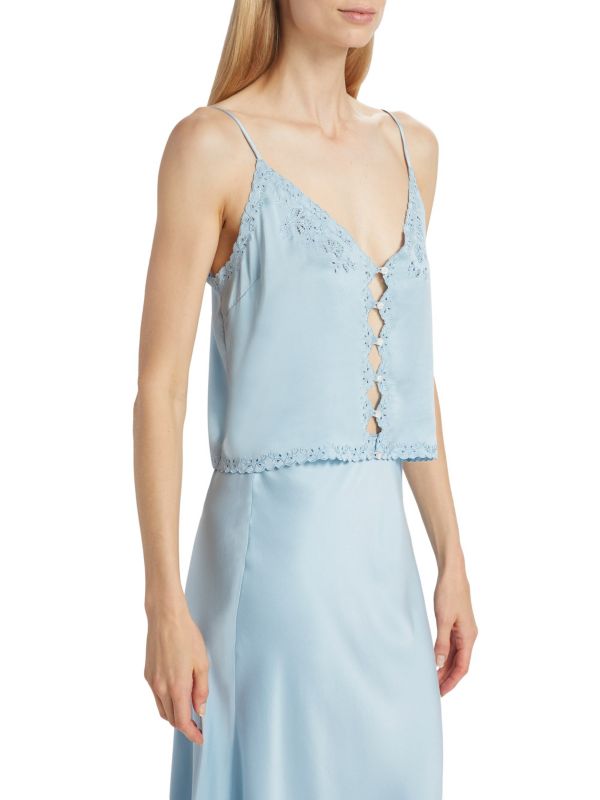 Crafted from 100% luxurious silk, the Elise Silk Crop Camisole by D Ô E N showcases a refined slip silhouette enhanced by openwork front buttons. Its delicate embroidered trim adds subtle elegance to the sleeveless design, while adjustable straps ensure a perfect fit. Featuring a flattering V-neck and tailored button-front closure, this piece combines comfort and sophistication. 