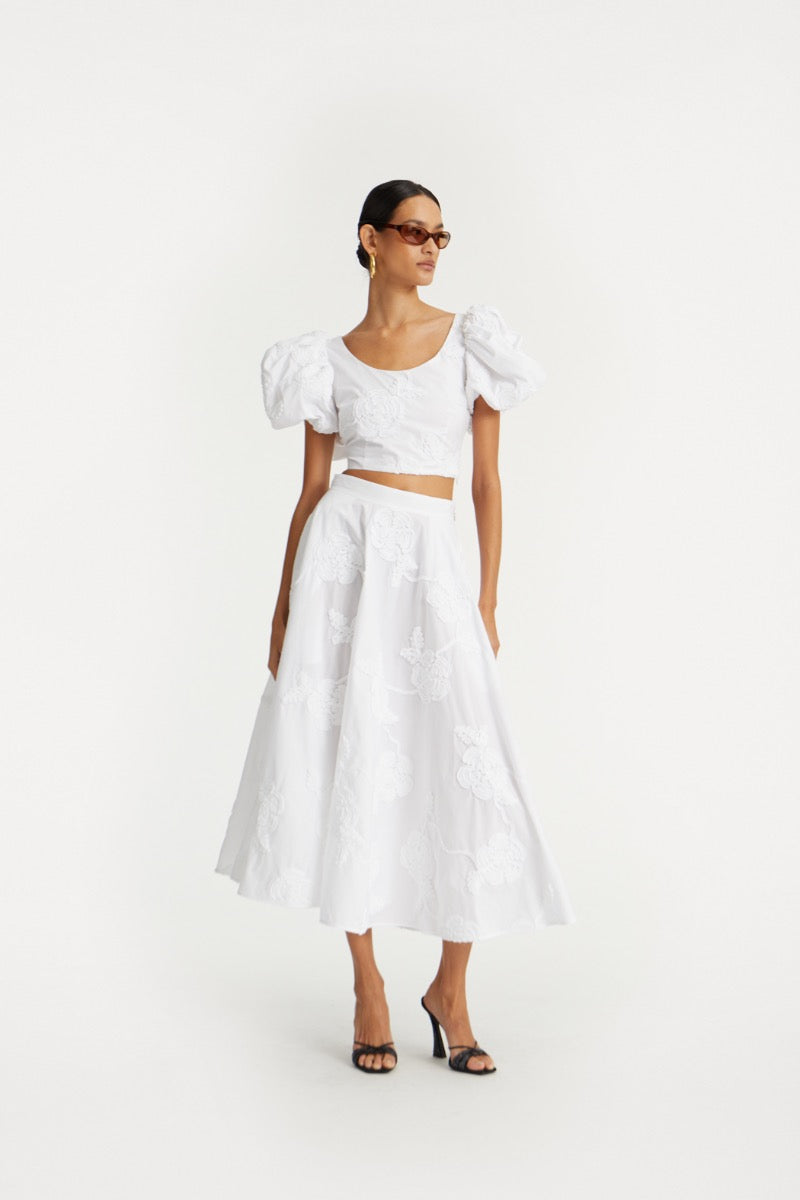 The Flower Maxi Skirt in Bright White combines elegance with comfort through its high-waisted design and voluminous flare, offering a flattering silhouette. Meticulously crafted with tonal floral embroidery, this skirt adds subtle sophistication to any outfit. Soft gathers at the waistband enhance its shape while a concealed side zipper ensures a seamless fit, making it a refined choice for both casual and formal occasions.