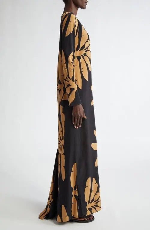 The Southwestern Long Sleeve Maxi Dress by Johanna Ortiz showcases a striking tropical frond pattern that captures a vibrant, nature-inspired aesthetic. Designed in a tunic silhouette, it features a daring chest cutout paired with a sophisticated jewel neckline, balancing boldness with elegance. The long sleeves provide added coverage, making it suitable for various occasions while maintaining a flowy, comfortable fit typical of maxi dresses. This piece blends artistic design with wearable sophistication, i