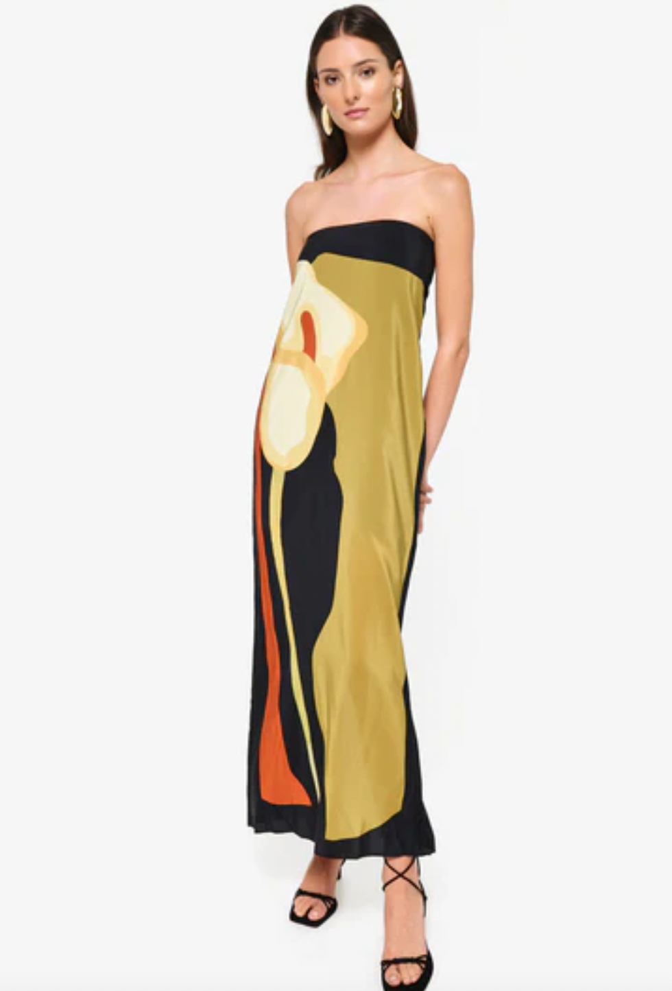 The Dalva Dress offers an elegant blend of sophistication and comfort with its strapless, column silhouette crafted from luxurious silk. Lined with the exclusive 'Calla' print, it provides both style and a smooth fit. The added elastic ensures secure support, while the back slit enhances mobility and adds a subtle allure. An invisible zipper completes the design for a flawless finish, making it an ideal choice for any refined occasion. Designed by Laura Cangussu in collaboration with Couper.