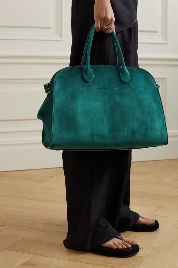 Crafted in Italy from smooth suede, the Margaux Air Suede Tote by The Row offers a softly structured silhouette enhanced by adjustable buckled sides for a customizable fit. Its thoughtful interior pockets provide secure storage for your essentials, merging elegant design with practical functionality. Made from 100% leather, this tote combines refined craftsmanship with everyday utility.
