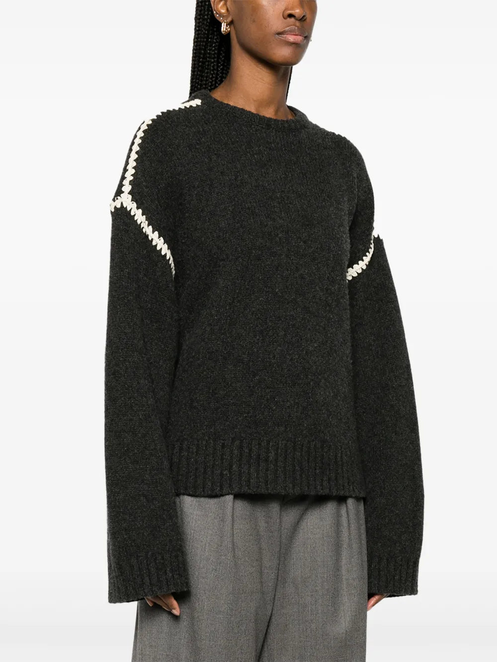 This TOTEME embroidered wool jumper combines minimalist design with luxurious craftsmanship. Made in Italy from high-quality wool, it features a subtle mélange effect in anthracite grey, highlighted by contrasting white whipstitch detailing. The knitted construction offers warmth and durability, while the crew neck, drop shoulders, and ribbed cuffs and hem provide a refined fit and comfortable wear. Ideal for layering or as a statement piece, this jumper balances understated elegance with standout details.