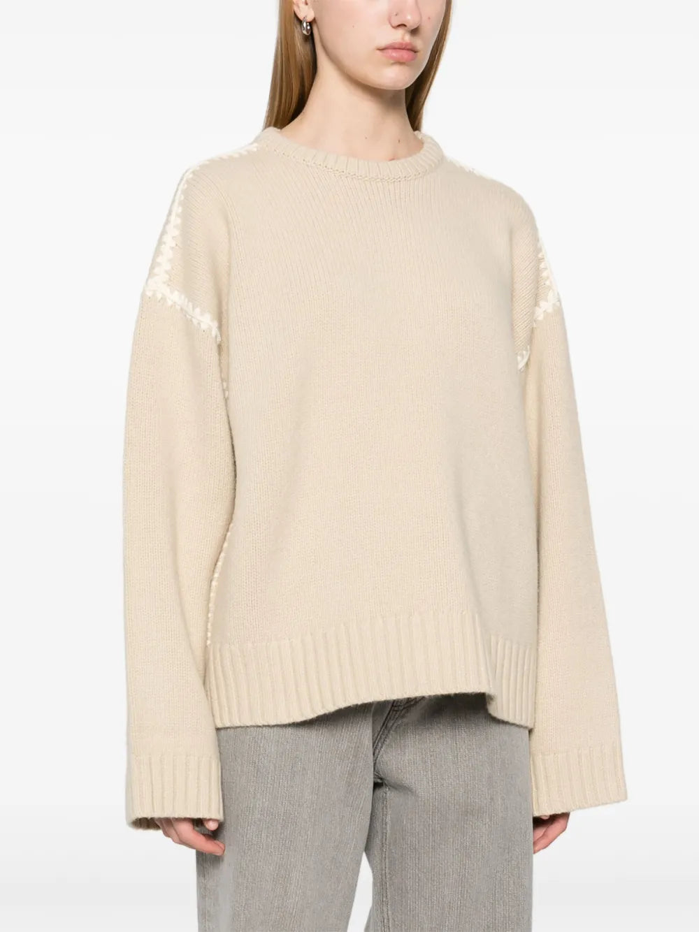 This embroidered wool jumper by Toteme combines minimalist design with luxurious craftsmanship. Made in Italy from high-quality wool, it features a subtle mélange effect in anthracite grey, highlighted by contrasting white whipstitch detailing. The knitted construction offers warmth and durability, while the crew neck, drop shoulders, and ribbed cuffs and hem provide a refined fit and comfortable wear. 