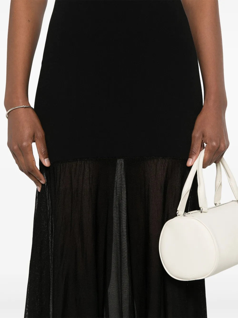 This black evening maxi dress by Toteme features a fine knit fabric with a panelled design that enhances its structured fit. The scoop neck and sleeveless cut create an elegant silhouette, while the unlined construction offers comfortable wear. The flared skirt flows gracefully into a long length, making it a sophisticated choice for formal occasions.