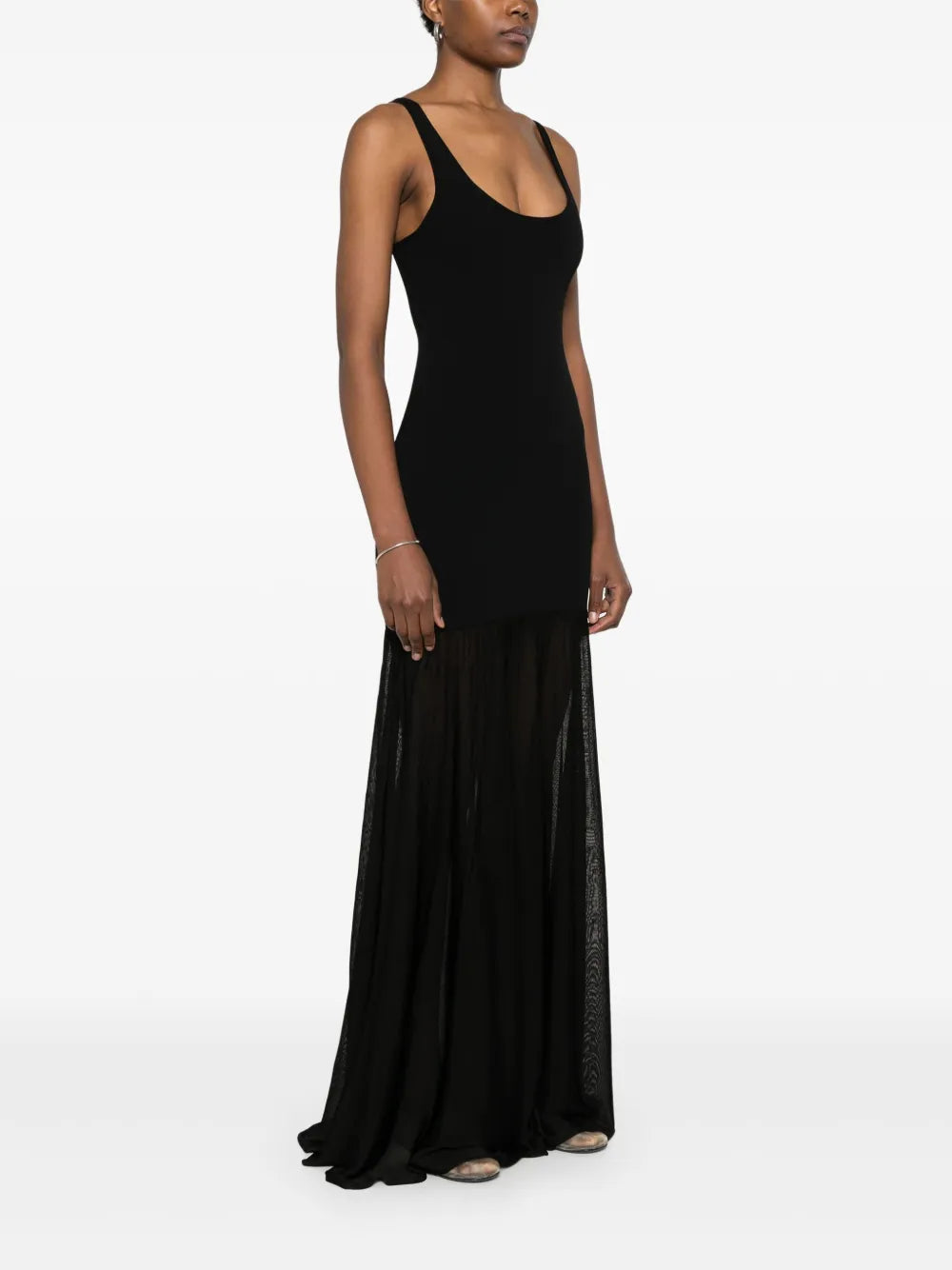 This black evening maxi dress by Toteme features a fine knit fabric with a panelled design that enhances its structured fit. The scoop neck and sleeveless cut create an elegant silhouette, while the unlined construction offers comfortable wear. The flared skirt flows gracefully into a long length, making it a sophisticated choice for formal occasions.