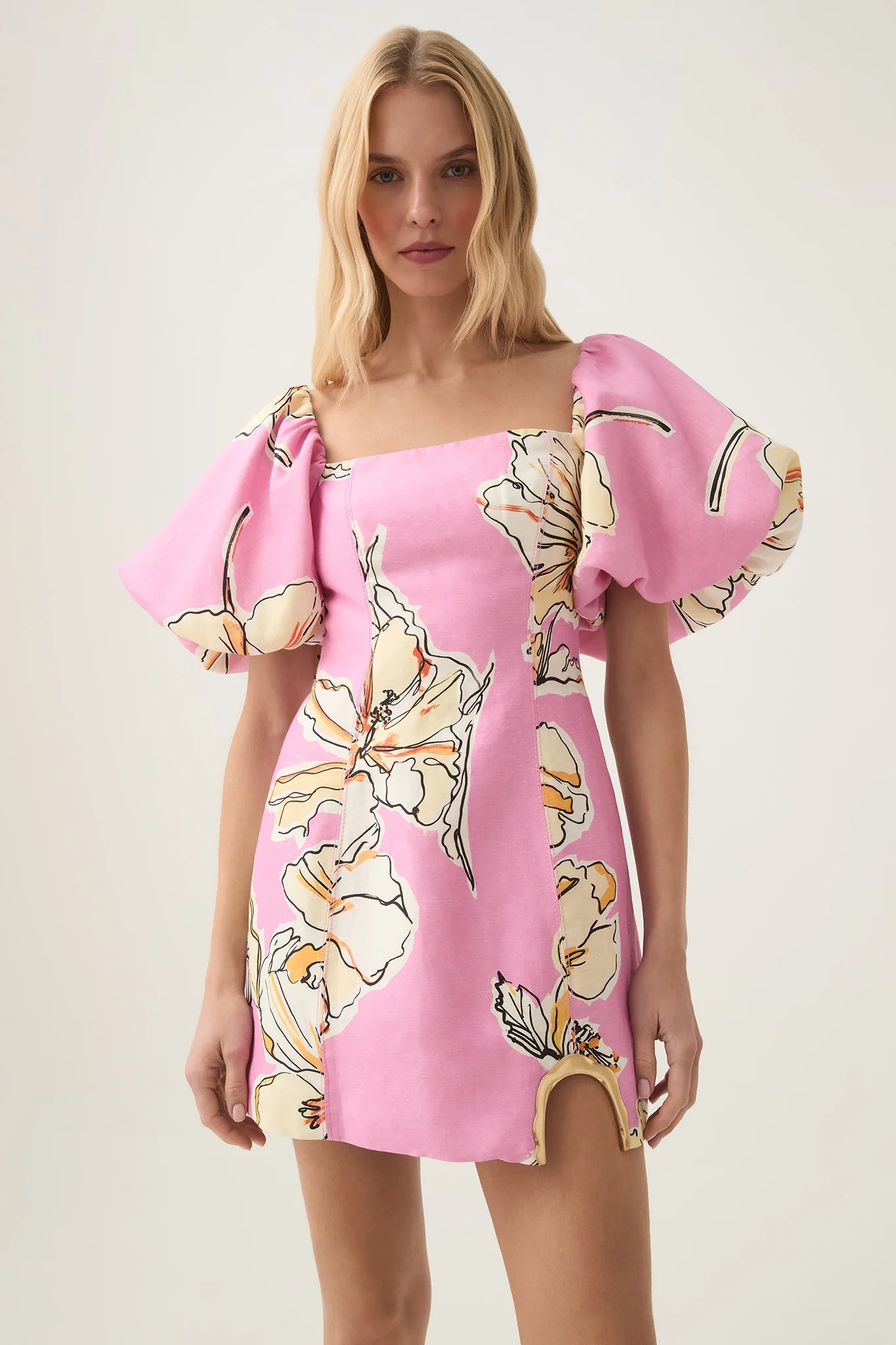The Flourish Mini Dress features a modern straight neckline and elegant puff sleeves with stretch cuffs for a tailored fit. Its distinctive curved side cut-out with metal detail adds a sophisticated edge, highlighting the silhouette. Designed with a zip, hook, and eye closure, this lined dress ensures both comfort and a smooth finish, making it an ideal choice for refined, stylish occasions.