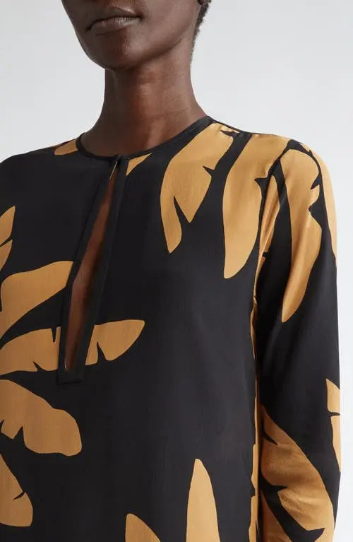 The Southwestern Long Sleeve Maxi Dress by Johanna Ortiz showcases a striking tropical frond pattern that captures a vibrant, nature-inspired aesthetic. Designed in a tunic silhouette, it features a daring chest cutout paired with a sophisticated jewel neckline, balancing boldness with elegance. The long sleeves provide added coverage, making it suitable for various occasions while maintaining a flowy, comfortable fit typical of maxi dresses. This piece blends artistic design with wearable sophistication, i