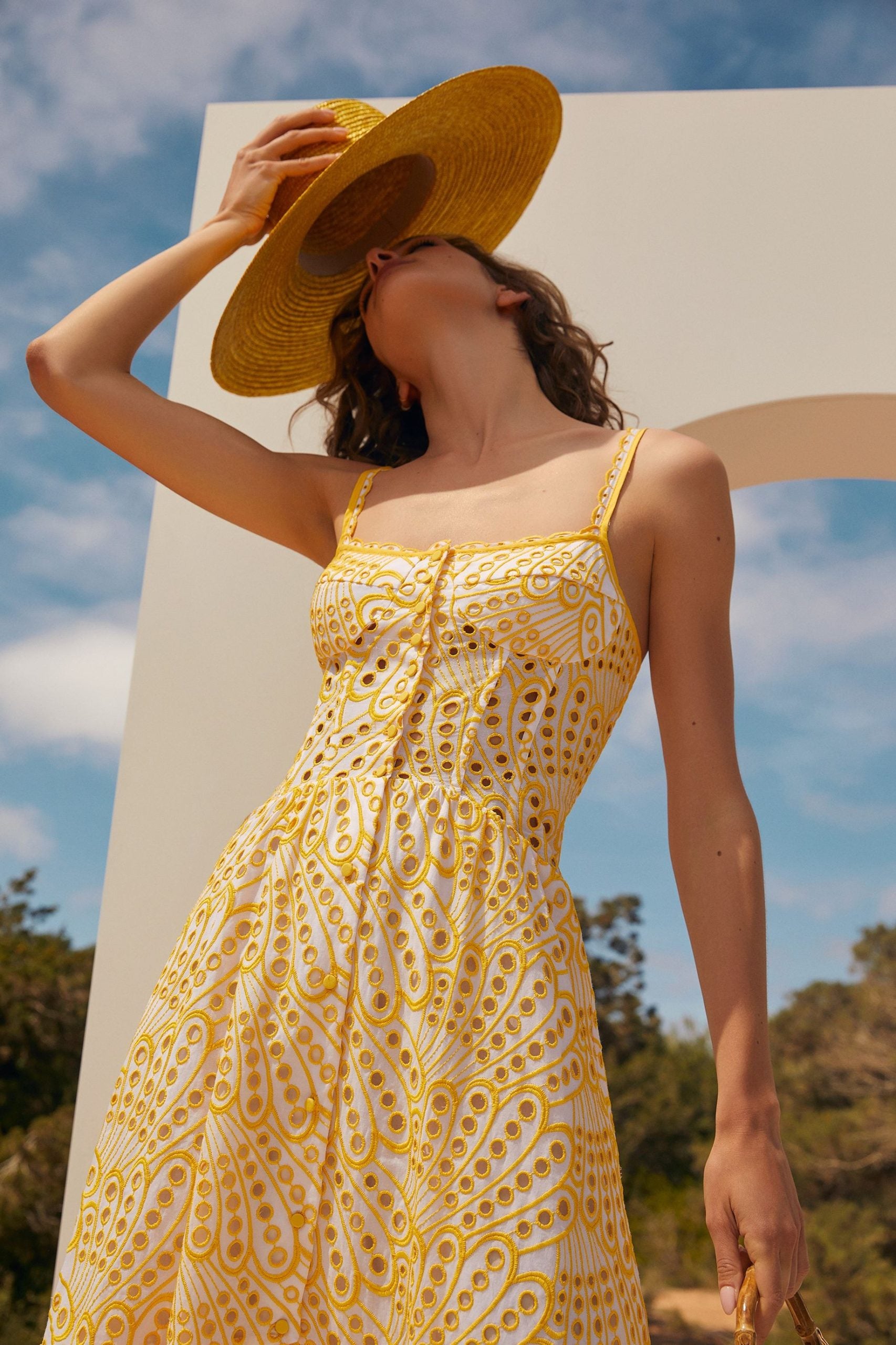 The Irene Dress by Charo Ruiz Ibiza features a front button design that allows for a full opening, enhancing ease and elegance. Crafted from partially lined embroidered batiste, it boasts a corseted bodice with a Balconette neckline that sculpts the silhouette. The dress culminates in a striking skirt, flowing into a dramatic ruffle made from the same delicate openwork fabric, combining structure with a graceful, airy finish.