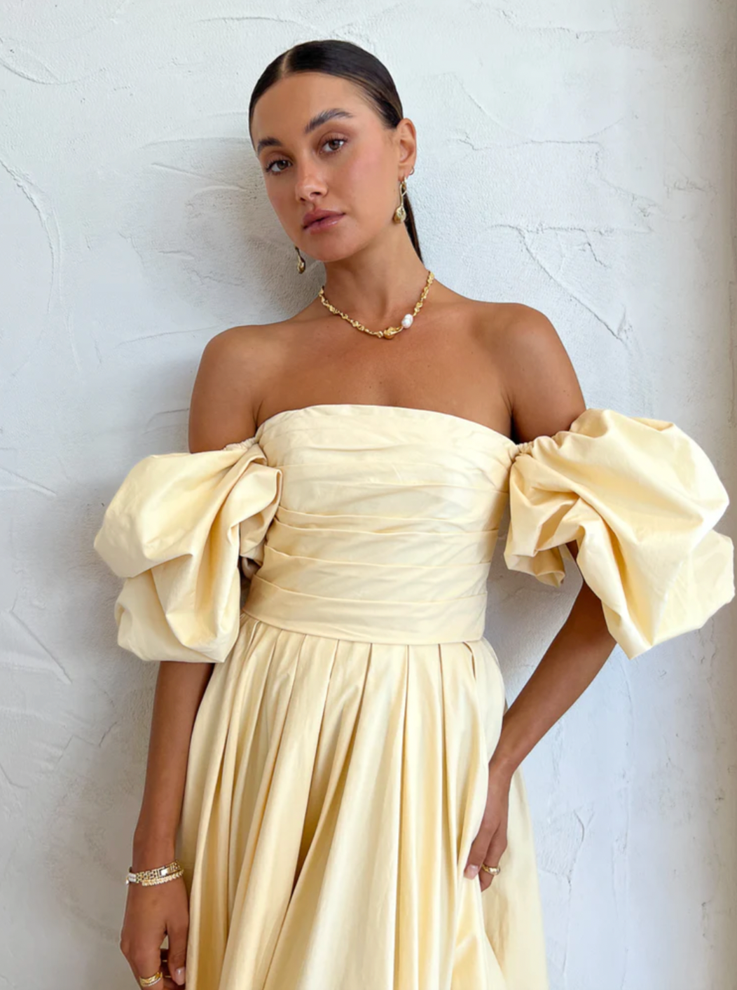 The Matilda Puff Sleeve Midi Dress in Lemon by Leo Lin combines timeless elegance with modern design. Made from soft cotton, it features a strapless straight neckline and delicate puffed short sleeves, complemented by a hand-draped bodice. The dress flows into a gathered, voluminous midi skirt, perfect for garden parties, summer soirees, and wedding celebrations. This dress offers a refined silhouette that enhances confidence and comfort throughout your special occasions.