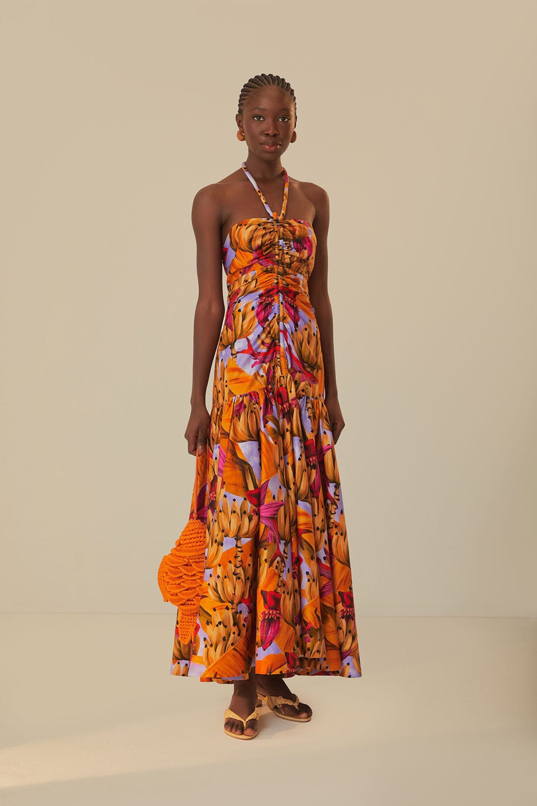Elevate your style with the Lilac Banana Forest Maxi Dress by FARM Rio. Made from 100% certified organic cotton, this dress features a halter neckline and flowy silhouette, adorned with a charming banana forest print. Sustainable and soft to the touch, it's perfect for any occasion.