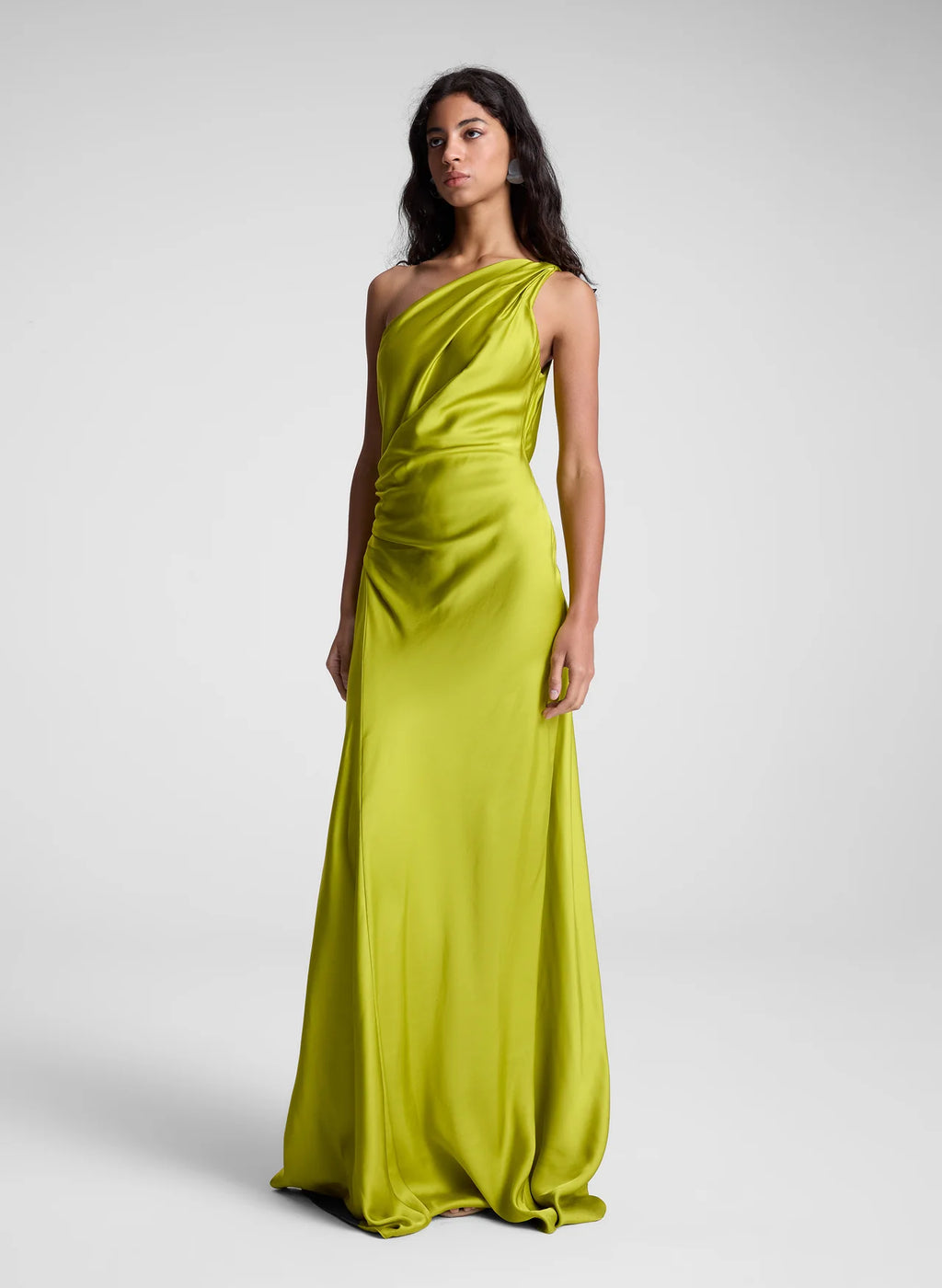 The Aster Satin One Shoulder Gown by A.L.C in radiant chartreuse is expertly crafted from fluid satin, delivering a graceful drape that enhances movement. Its one-shoulder design features delicate pleating at the shoulder and waist, sculpting a refined silhouette with architectural elegance. The asymmetrical cut accentuates the gown’s fluidity, making it a standout piece for sophisticated occasions.