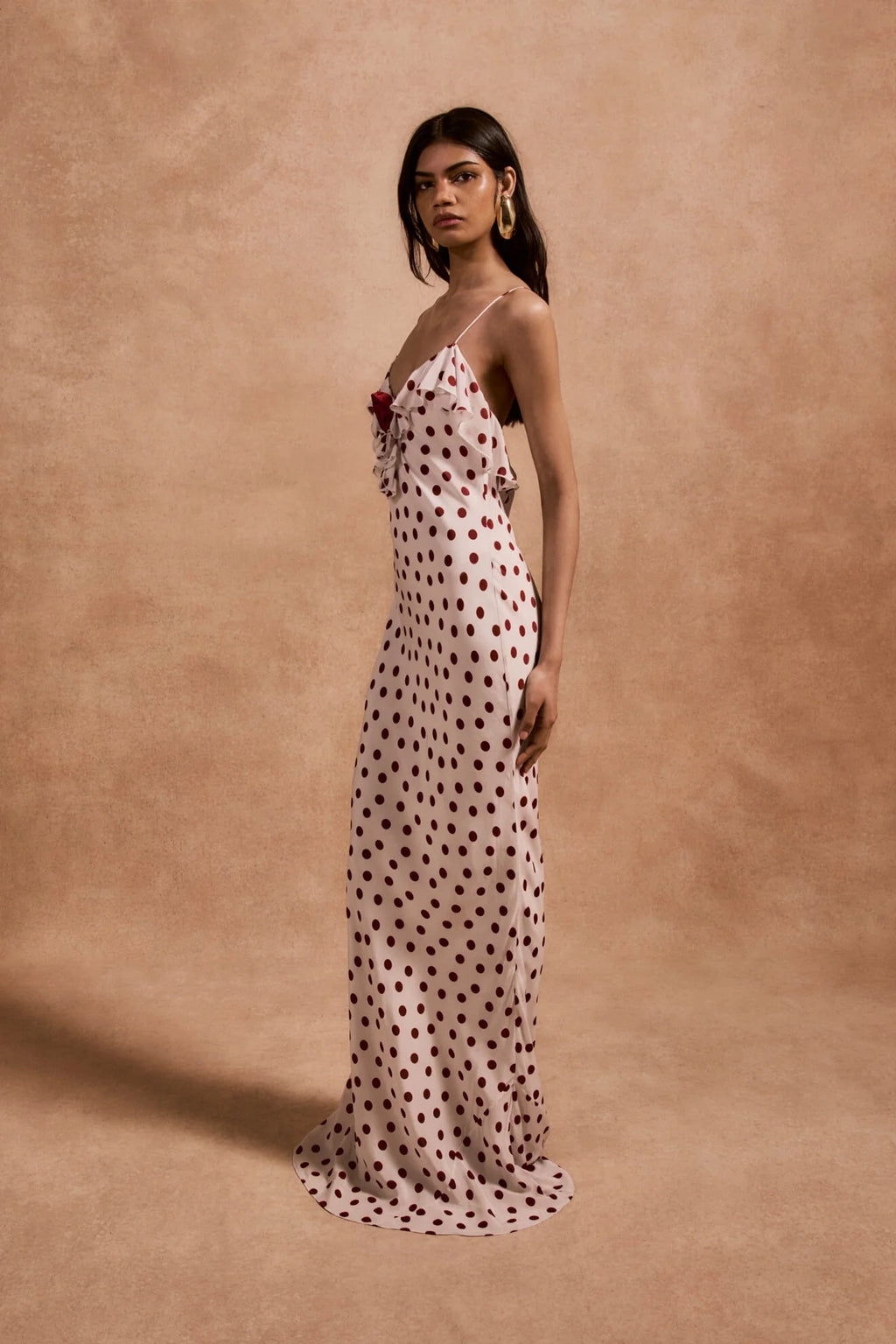 The Esperanza Long Dress by De La Vali combines expert craftsmanship with timeless elegance. Made from 100% viscose crepe de chine, its bias-cut silhouette drapes gracefully, enhanced by an ivory and red polka dot pattern. The ruffled bust adds a refined detail that elevates the dress’s charm. Perfect for formal events or stylish evenings, it pairs beautifully with strappy sandals and delicate jewelry to create a sophisticated, polished look.