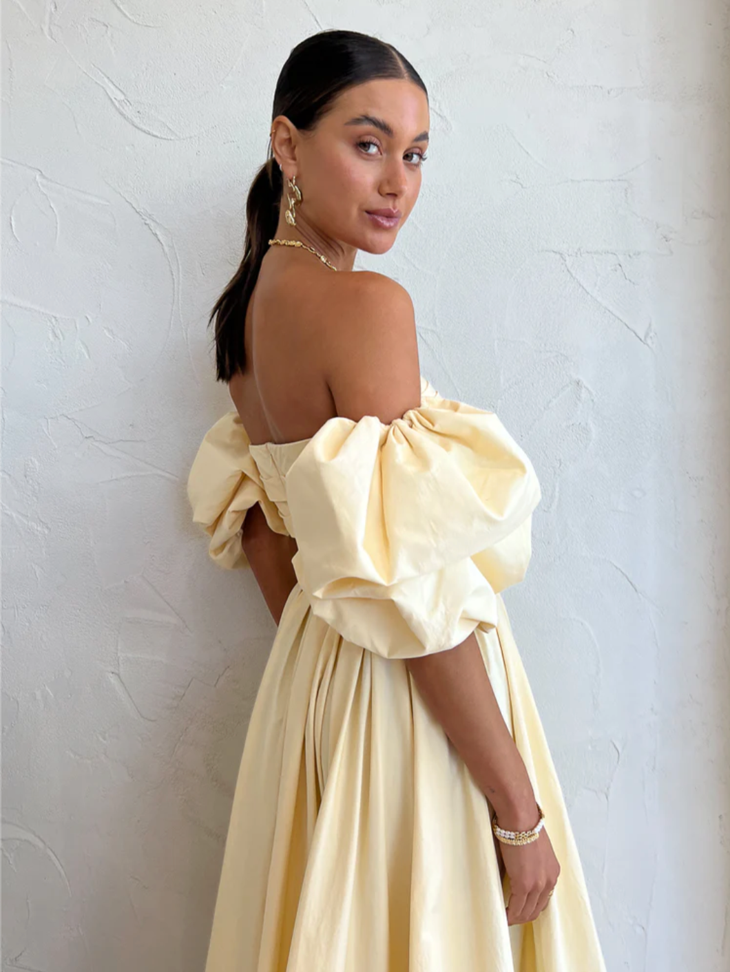 The Matilda Puff Sleeve Midi Dress in Lemon by Leo Lin combines timeless elegance with modern design. Made from soft cotton, it features a strapless straight neckline and delicate puffed short sleeves, complemented by a hand-draped bodice. The dress flows into a gathered, voluminous midi skirt, perfect for garden parties, summer soirees, and wedding celebrations. This dress offers a refined silhouette that enhances confidence and comfort throughout your special occasions.