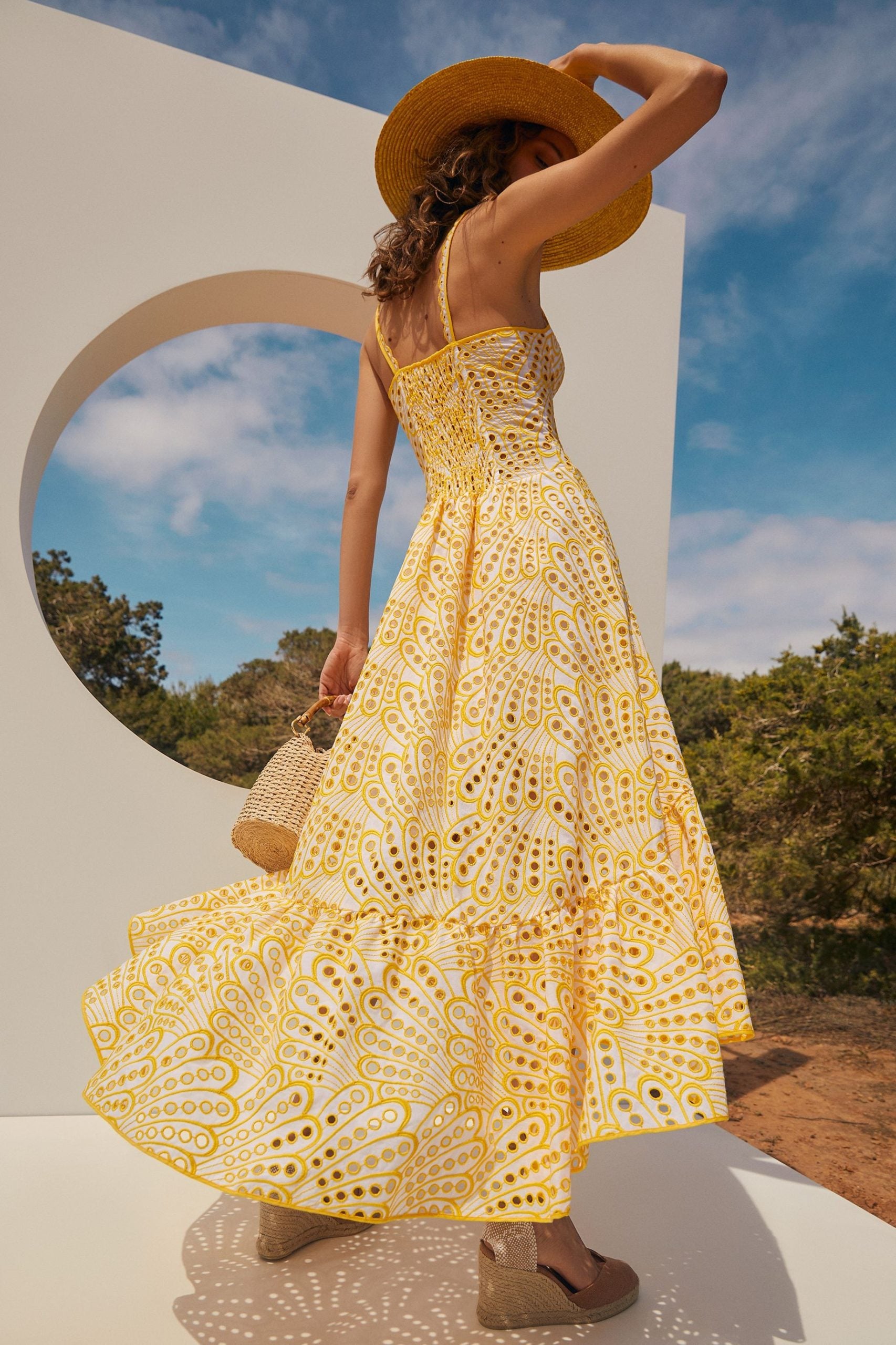 The Irene Dress by Charo Ruiz Ibiza features a front button design that allows for a full opening, enhancing ease and elegance. Crafted from partially lined embroidered batiste, it boasts a corseted bodice with a Balconette neckline that sculpts the silhouette. The dress culminates in a striking skirt, flowing into a dramatic ruffle made from the same delicate openwork fabric, combining structure with a graceful, airy finish.
