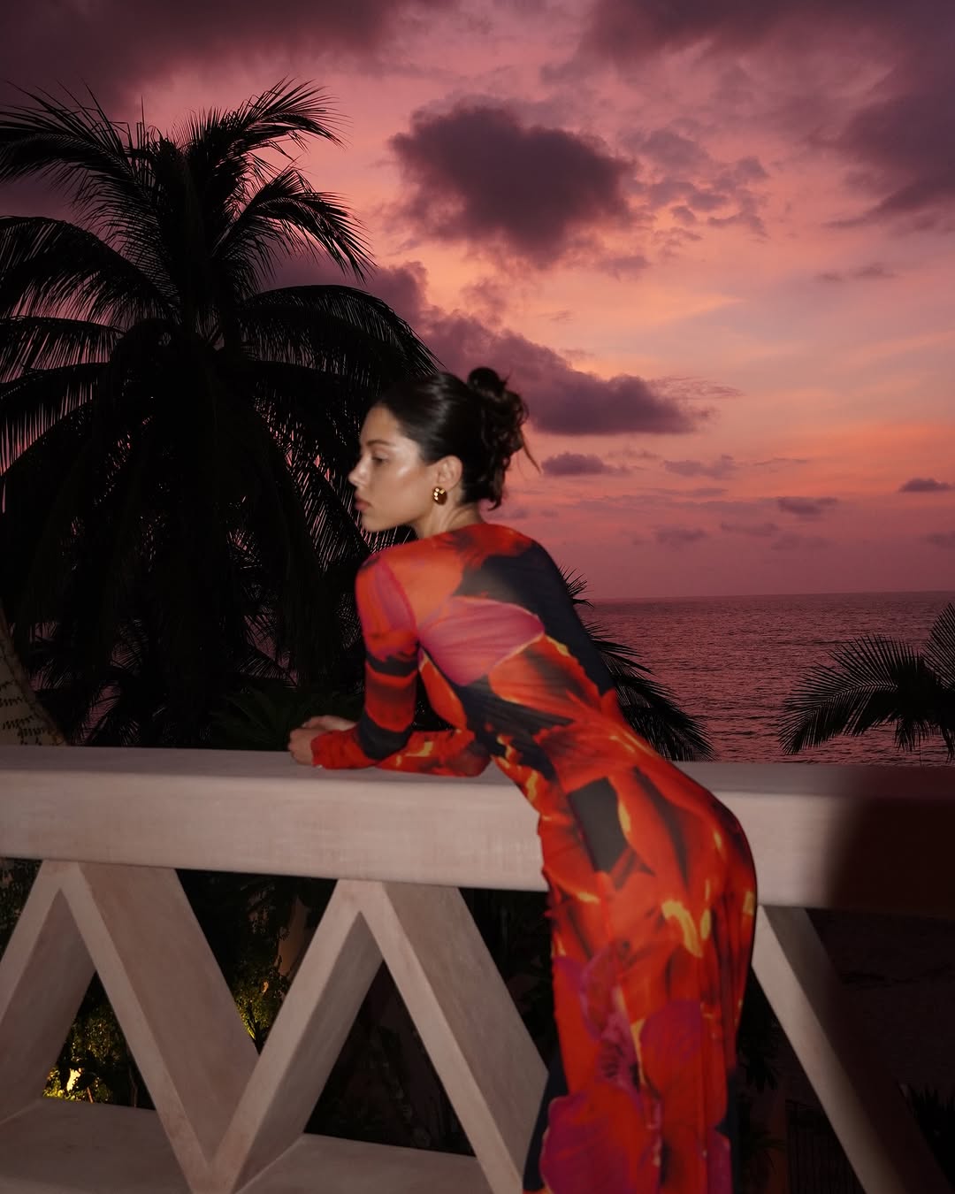 This full-length mesh maxi dress offers a sleek, form-fitting silhouette with its high neckline and long sleeves. Made from sheer, lightweight mesh, it features a unique bold repeat print that varies with each piece. Merrowed ruffle detailing on the sleeves and hem adds elegant sculptural texture. Designed for versatility, this dress effortlessly transitions from daytime sophistication to evening statement wear.