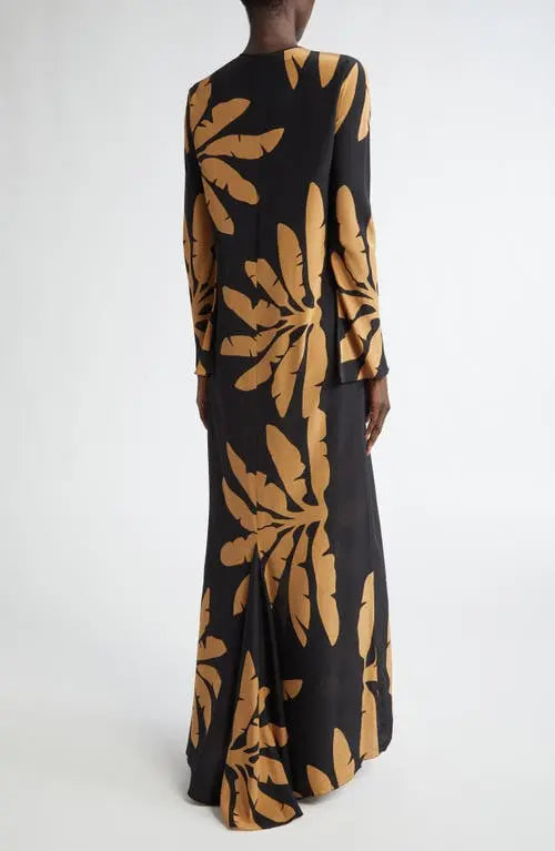The Southwestern Long Sleeve Maxi Dress by Johanna Ortiz showcases a striking tropical frond pattern that captures a vibrant, nature-inspired aesthetic. Designed in a tunic silhouette, it features a daring chest cutout paired with a sophisticated jewel neckline, balancing boldness with elegance. The long sleeves provide added coverage, making it suitable for various occasions while maintaining a flowy, comfortable fit typical of maxi dresses. This piece blends artistic design with wearable sophistication, i