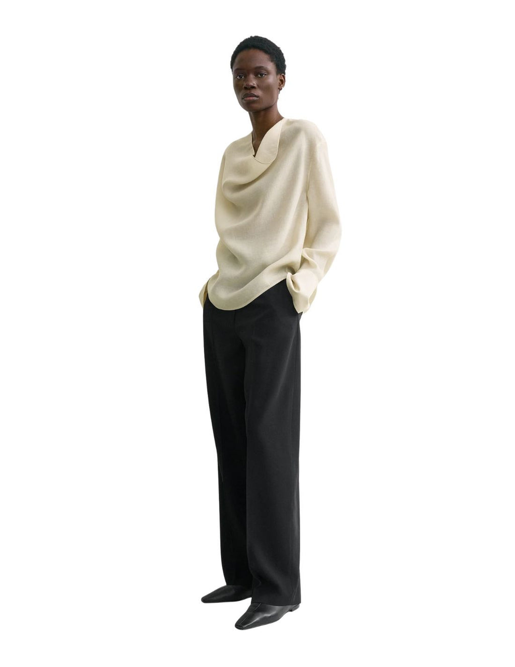 This TOTEME blouse combines refined craftsmanship with effortless style. Crafted from a luxurious blended wool in an elegant ecru shade, its oversized silhouette ensures comfort while maintaining a modern edge. The draped cowl neck creates a sophisticated focal point, complemented by long sleeves finished with buttoned cuffs for a polished look. The curved hem adds subtle fluidity, making this blouse a versatile piece that elevates both casual and formal ensembles with understated elegance.