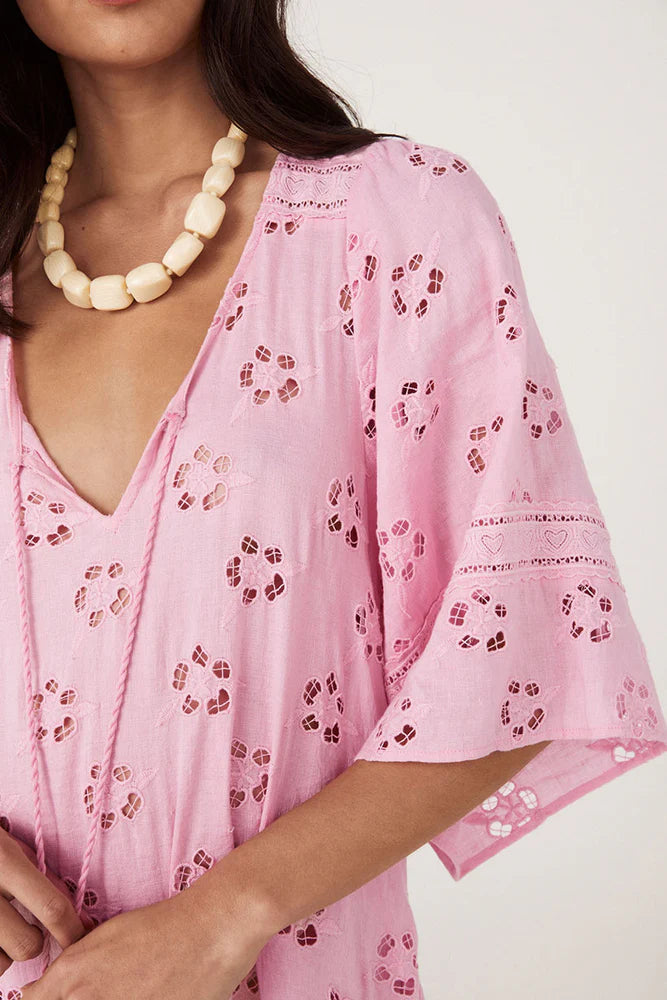 Step into a daydream with the Love Note Broderie Gown in Cosmos Pink, a gown that speaks of romance and delicate femininity. The soft pink hue, combined with custom embroidery and lace, lends an air of whimsy and beauty. A V-neckline with a keyhole opening at the centre front and side splits create a graceful, flowing silhouette, while flutter sleeves add a touch of fairytale magic. 