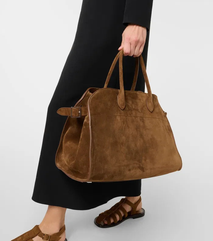 The Soft Margaux 15 Suede Tote Bag by The Row features a softly structured design crafted from supple calfskin suede, offering both elegance and durability. Its belted gusseted side panels provide a refined silhouette while allowing flexible storage capacity. Inside, the spacious interior is thoughtfully designed for organization, making it ideal for daily use with a sophisticated touch.