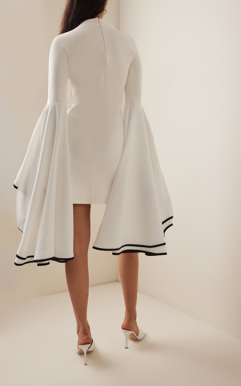 This Stretch Crepe Sleeve Dress by Proenza Schouler features a slim fit with a mock neck and exaggerated bell sleeves accented by contrast cuff trim. The mini hem and concealed back zip create a streamlined silhouette, designed to fit true to size. Pair it with statement heels in a matching colorway and style your hair in a sleek low bun for an elegant, polished look. Unlined for lightweight comfort, it’s perfect for occasions that call for refined sophistication.