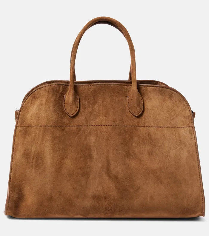 The Soft Margaux 15 Suede Tote Bag by The Row features a softly structured design crafted from supple calfskin suede, offering both elegance and durability. Its belted gusseted side panels provide a refined silhouette while allowing flexible storage capacity. Inside, the spacious interior is thoughtfully designed for organization, making it ideal for daily use with a sophisticated touch.
