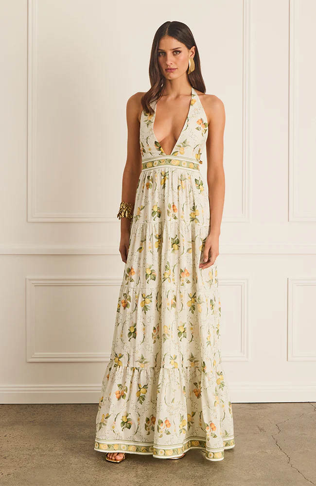 The Jacinta Maxi Dress in Aqua Blu showcases a delicate lemon print on a luxurious French linen and mulberry silk blend. Designed with a halter neck and plunging V-neckline, it offers a relaxed, flowing silhouette that adapts seamlessly from day to evening wear. Thoughtfully tailored for comfort on larger busts, it includes functional side pockets and a tie-back detail. Fully lined for a smooth finish, this dress combines elegance with practicality for a refined summer statement.