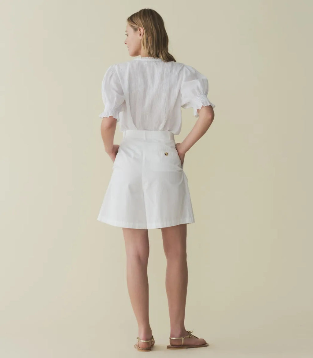 The Karlie Top by Doen is expertly crafted from lightweight ramie, offering a sheer, airy feel. Its Edwardian-inspired silhouette features a plunging V-neckline trimmed with delicate ruffles and intricate pintuck detailing along the yoke, back, and puffed sleeves. A central button line allows versatile styling, whether worn loosely or tucked in, making it an ideal match for high-waisted jeans. This top seamlessly blends timeless romantic details with contemporary functionality.