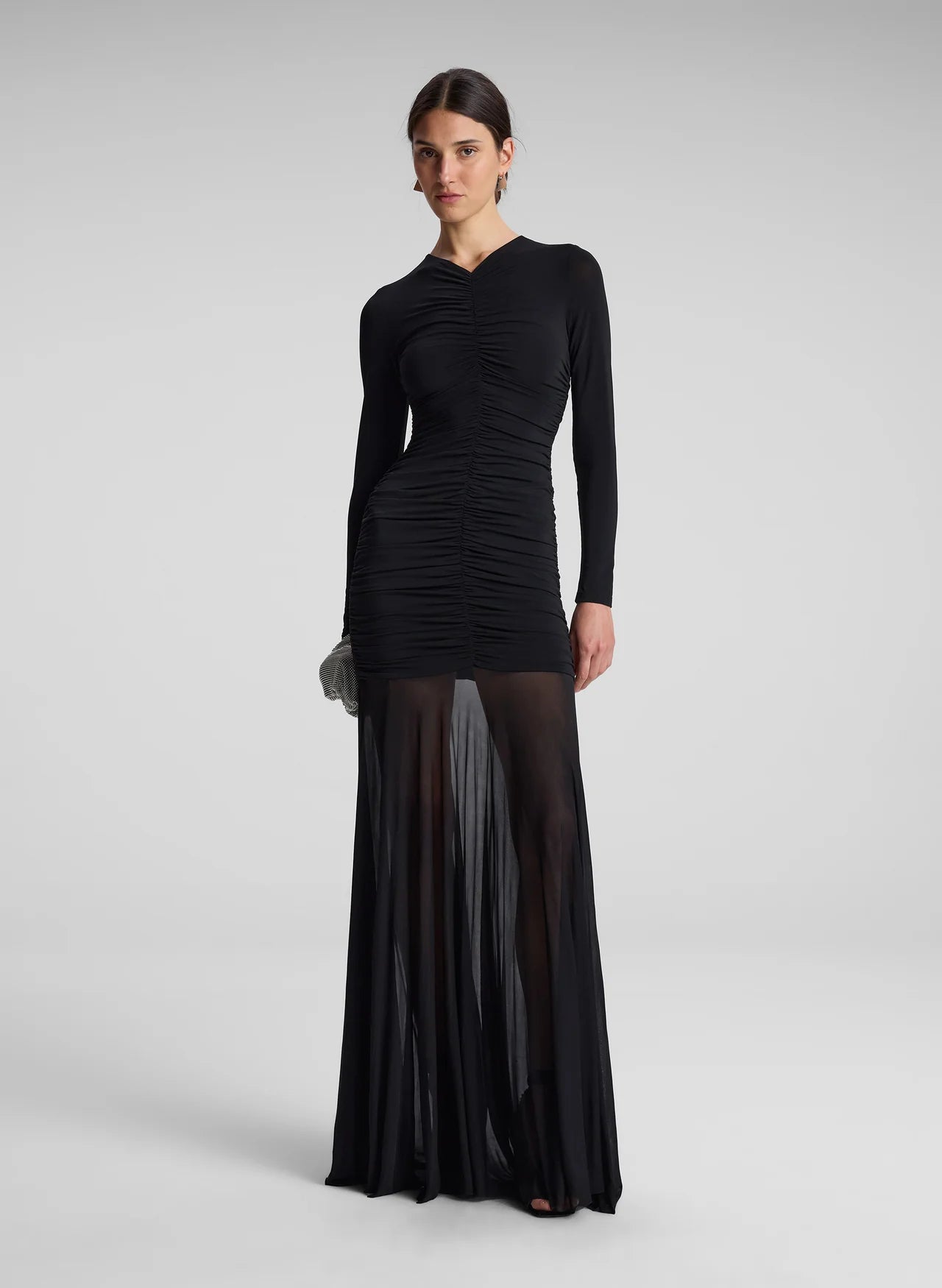 The Fawn Ruched Mesh Maxi Dress combines elegance and contemporary design through its sheer jersey fabric in timeless black. This full-length gown showcases a v-neckline with a delicately ruched bodice that enhances the silhouette, complemented by sheer sleeves for subtle sophistication. The pleated sheer skirt moves gracefully, offering fluidity and refined style suitable for formal occasions or evening wear.