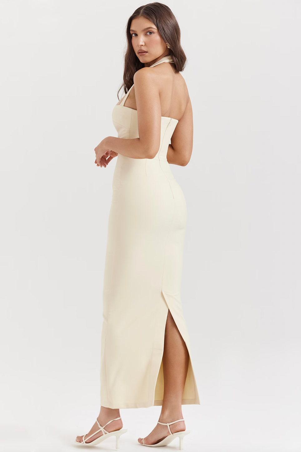The Mia Halter Dress offers a sleek, figure-hugging silhouette designed to flatter the female form. Crafted from stretch ecru crepe, it ensures both comfort and elegance. Distinctive decorative detailing along the front adds visual interest, while the corseted bodice strategically cinches the waist and enhances the bust, creating a refined and confident look.