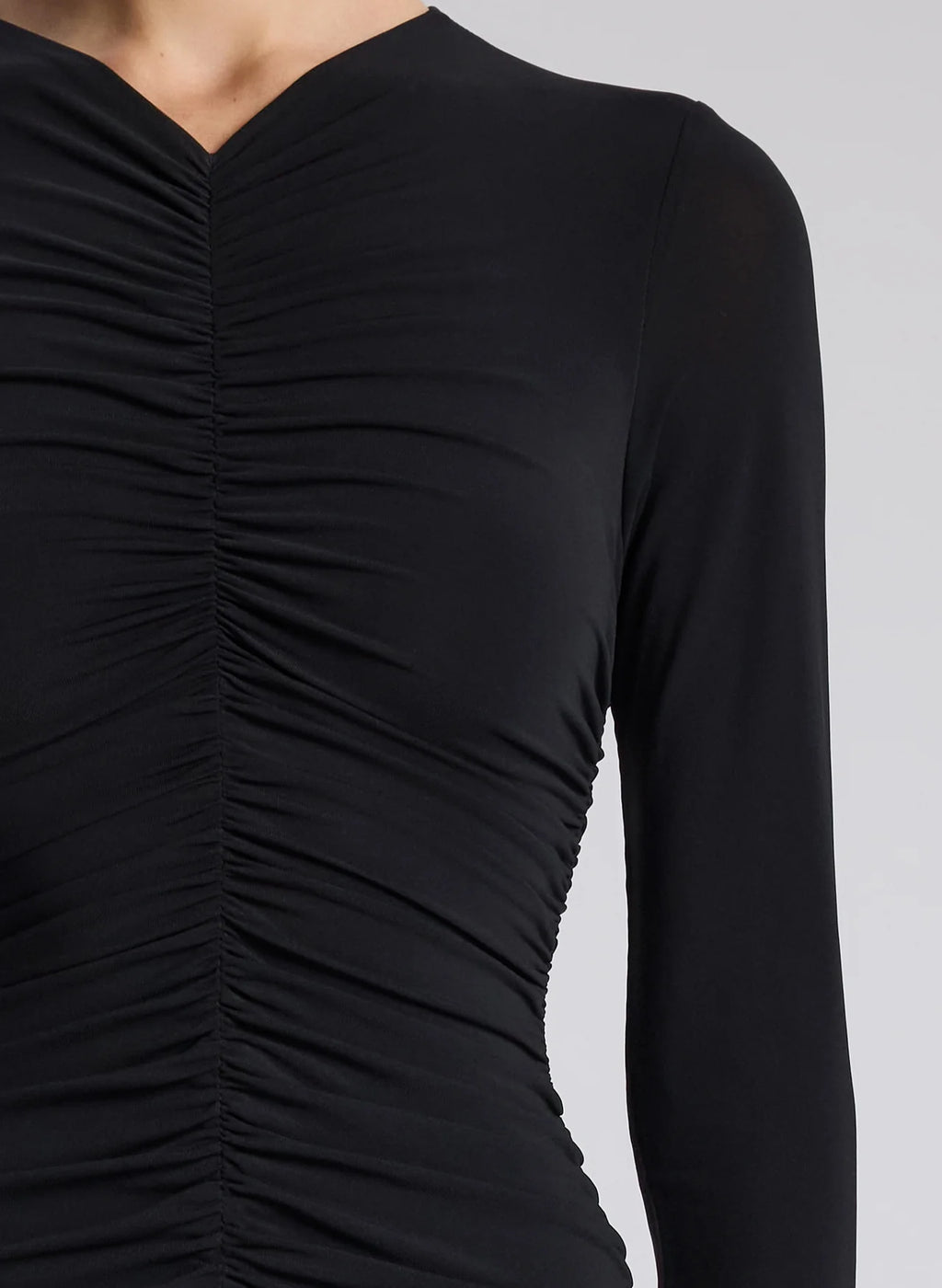 The Fawn Ruched Mesh Maxi Dress combines elegance and contemporary design through its sheer jersey fabric in timeless black. This full-length gown showcases a v-neckline with a delicately ruched bodice that enhances the silhouette, complemented by sheer sleeves for subtle sophistication. The pleated sheer skirt moves gracefully, offering fluidity and refined style suitable for formal occasions or evening wear.