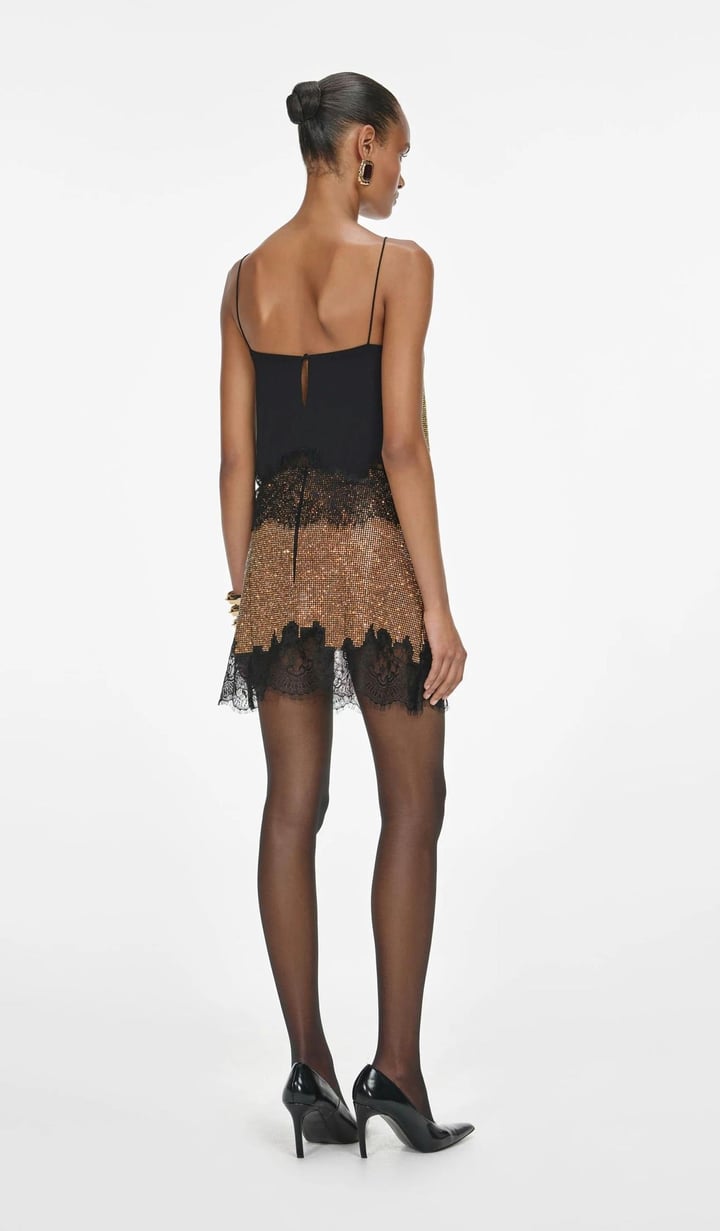Elevate your party wardrobe with the Champagne Crystal Top, designed for confident, stylish wear. This relaxed-fit top features sparkling champagne crystals and delicate lace trims at the hem, adding a refined boudoir touch. Fully lined for comfort and finished with a button closure at the back, it pairs effortlessly with matching skirts and heels for a standout look that lasts all night. 