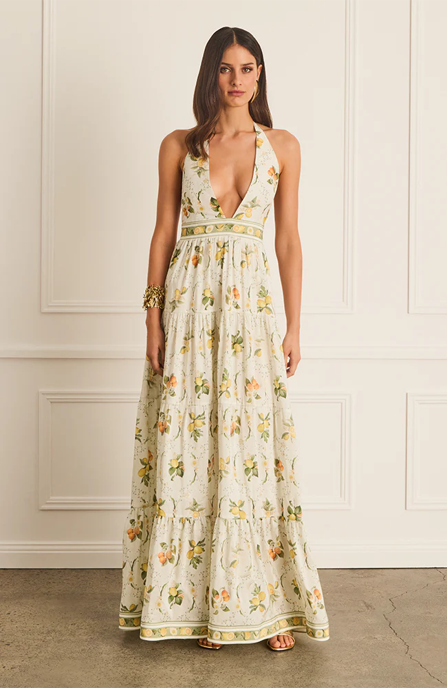 The Jacinta Maxi Dress in Aqua Blu showcases a delicate lemon print on a luxurious French linen and mulberry silk blend. Designed with a halter neck and plunging V-neckline, it offers a relaxed, flowing silhouette that adapts seamlessly from day to evening wear. Thoughtfully tailored for comfort on larger busts, it includes functional side pockets and a tie-back detail. Fully lined for a smooth finish, this dress combines elegance with practicality for a refined summer statement.