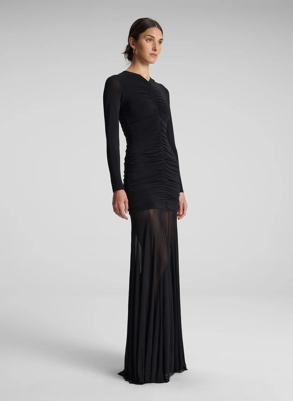 The Fawn Ruched Mesh Maxi Dress combines elegance and contemporary design through its sheer jersey fabric in timeless black. This full-length gown showcases a v-neckline with a delicately ruched bodice that enhances the silhouette, complemented by sheer sleeves for subtle sophistication. The pleated sheer skirt moves gracefully, offering fluidity and refined style suitable for formal occasions or evening wear.