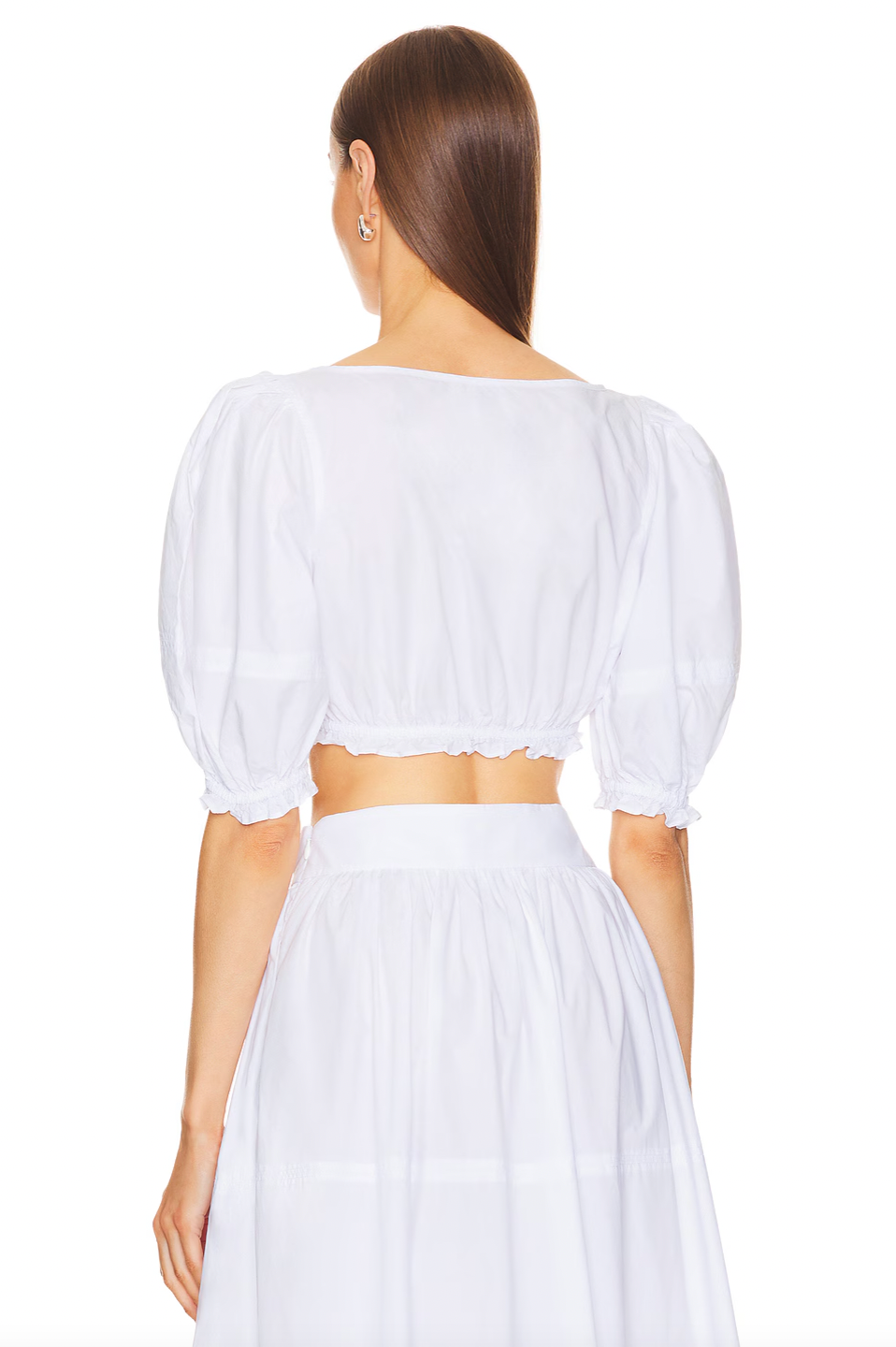 The Poplin Cropped Peasant Top by Helsa features airy puff sleeves with elastic cuffs for comfortable movement and a flattering silhouette. A delicate bow detail at the front adds a subtle touch of charm, while the elastic underband ensures a secure yet flexible fit. Crafted from lightweight poplin fabric, this top offers breathability and a crisp, polished appearance ideal for warm-weather styling.