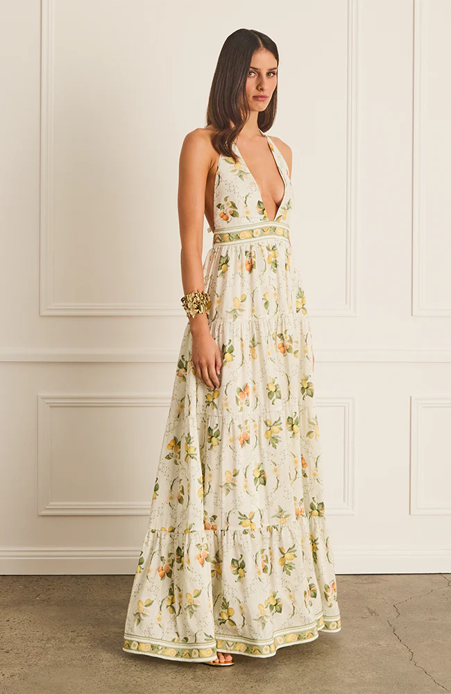 The Jacinta Maxi Dress in Aqua Blu showcases a delicate lemon print on a luxurious French linen and mulberry silk blend. Designed with a halter neck and plunging V-neckline, it offers a relaxed, flowing silhouette that adapts seamlessly from day to evening wear. Thoughtfully tailored for comfort on larger busts, it includes functional side pockets and a tie-back detail. Fully lined for a smooth finish, this dress combines elegance with practicality for a refined summer statement.