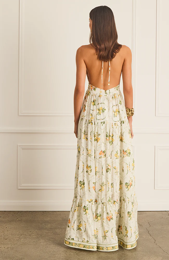 The Jacinta Maxi Dress in Aqua Blu showcases a delicate lemon print on a luxurious French linen and mulberry silk blend. Designed with a halter neck and plunging V-neckline, it offers a relaxed, flowing silhouette that adapts seamlessly from day to evening wear. Thoughtfully tailored for comfort on larger busts, it includes functional side pockets and a tie-back detail. Fully lined for a smooth finish, this dress combines elegance with practicality for a refined summer statement.