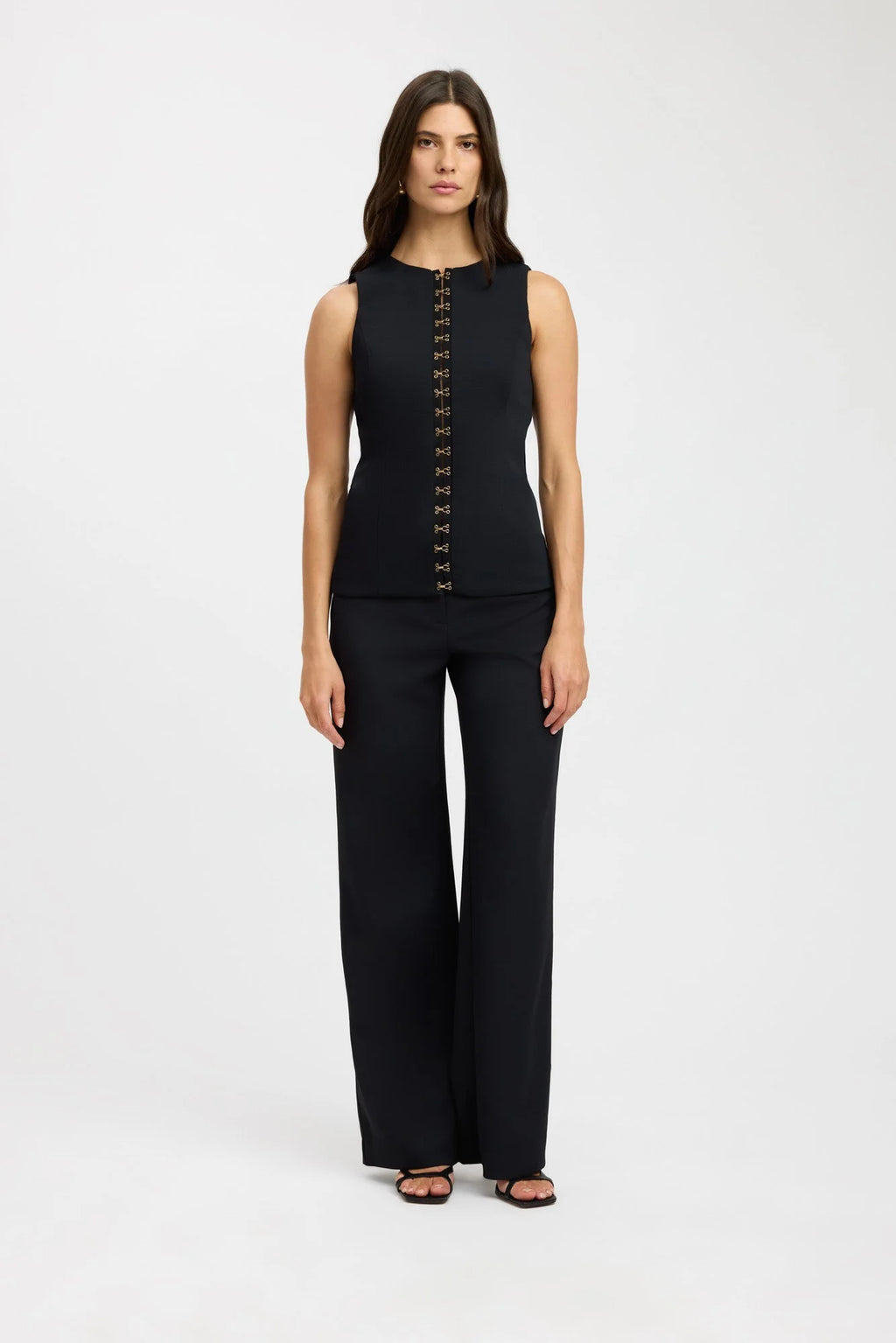 Elevate your fashion game with the Oyster Hook Crew Top in Black. Made from luxurious suiting fabric, this top boasts a sophisticated high neckline and flattering flared hemline. The adjustable gold hook and eye details add a touch of elegance and allow for customizable styling. Make a statement with this must-have piece.