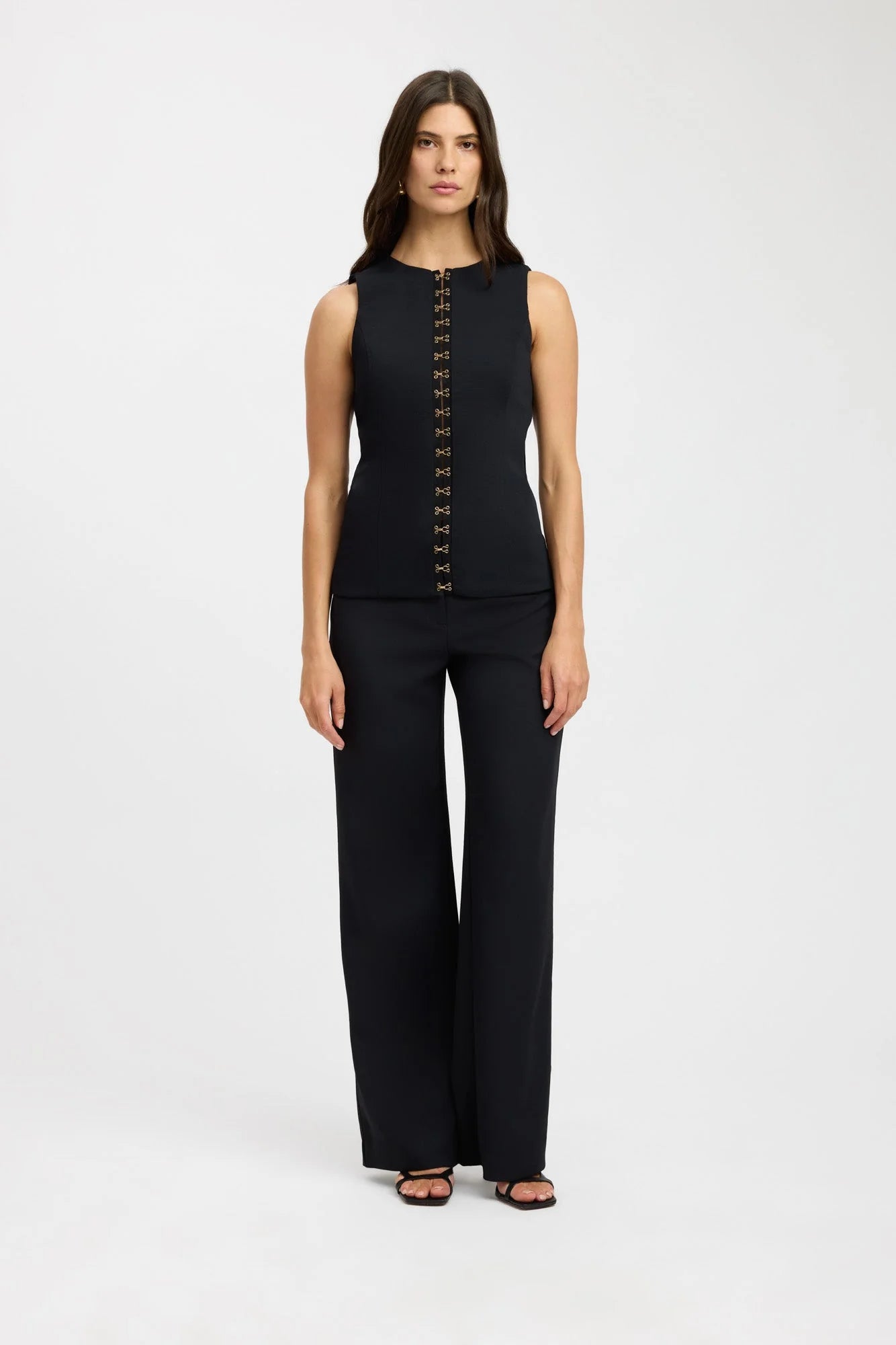 Elevate your fashion game with the Oyster Hook Crew Top in Black. Made from luxurious suiting fabric, this top boasts a sophisticated high neckline and flattering flared hemline. The adjustable gold hook and eye details add a touch of elegance and allow for customizable styling. Make a statement with this must-have piece.