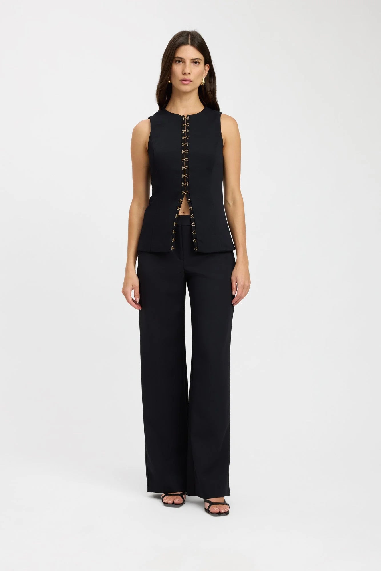 Elevate your fashion game with the Oyster Hook Crew Top in Black. Made from luxurious suiting fabric, this top boasts a sophisticated high neckline and flattering flared hemline. The adjustable gold hook and eye details add a touch of elegance and allow for customizable styling. Make a statement with this must-have piece.