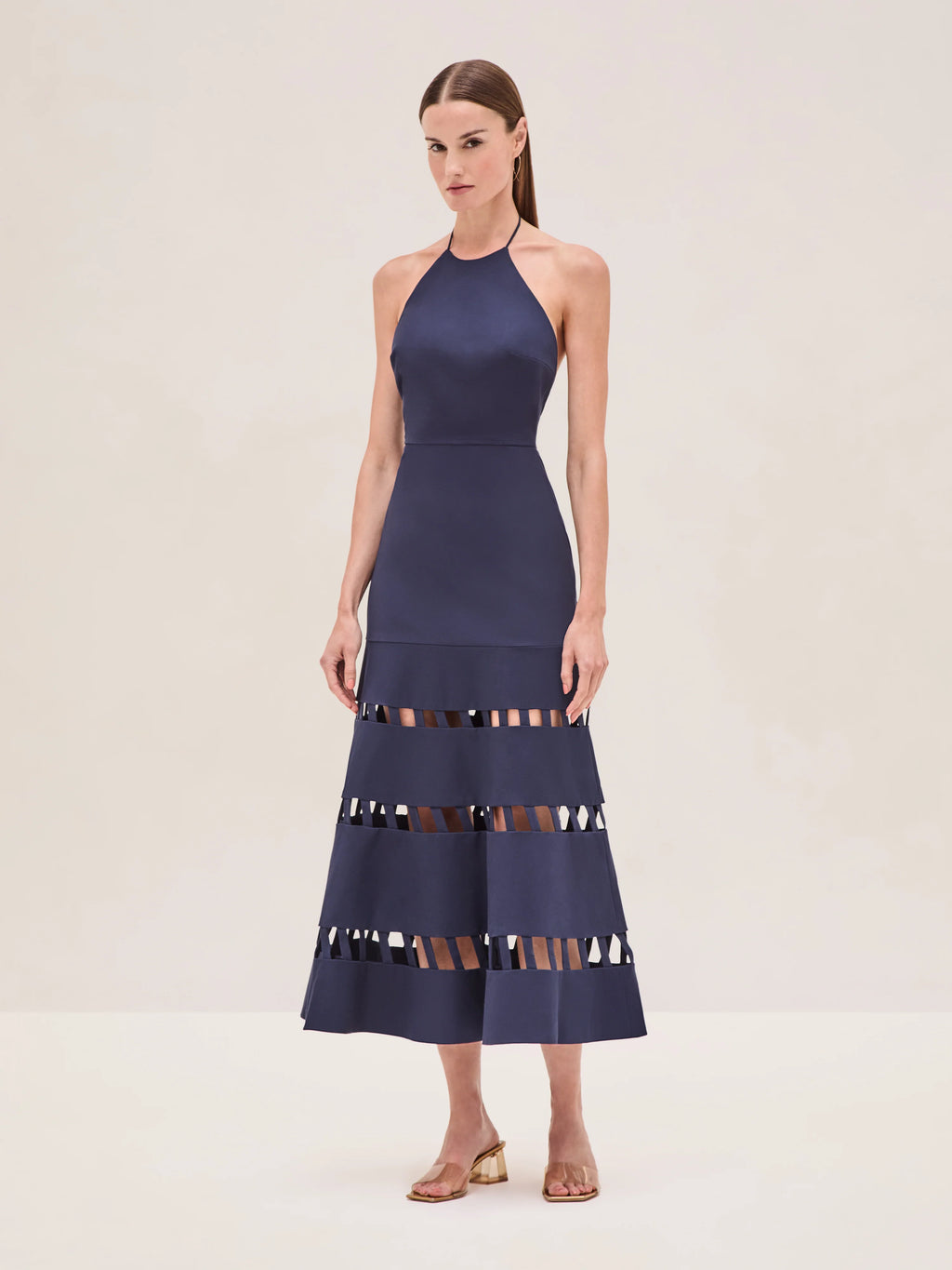 The Janessa Dress by Alexis combines classic comfort with modern detail through its breathable cotton fabric and halter neckline. Its midi length offers versatile styling options, while the distinctive cut-out ladder detailing adds an elegant touch of texture and visual interest, making it a refined choice for warm-weather occasions.