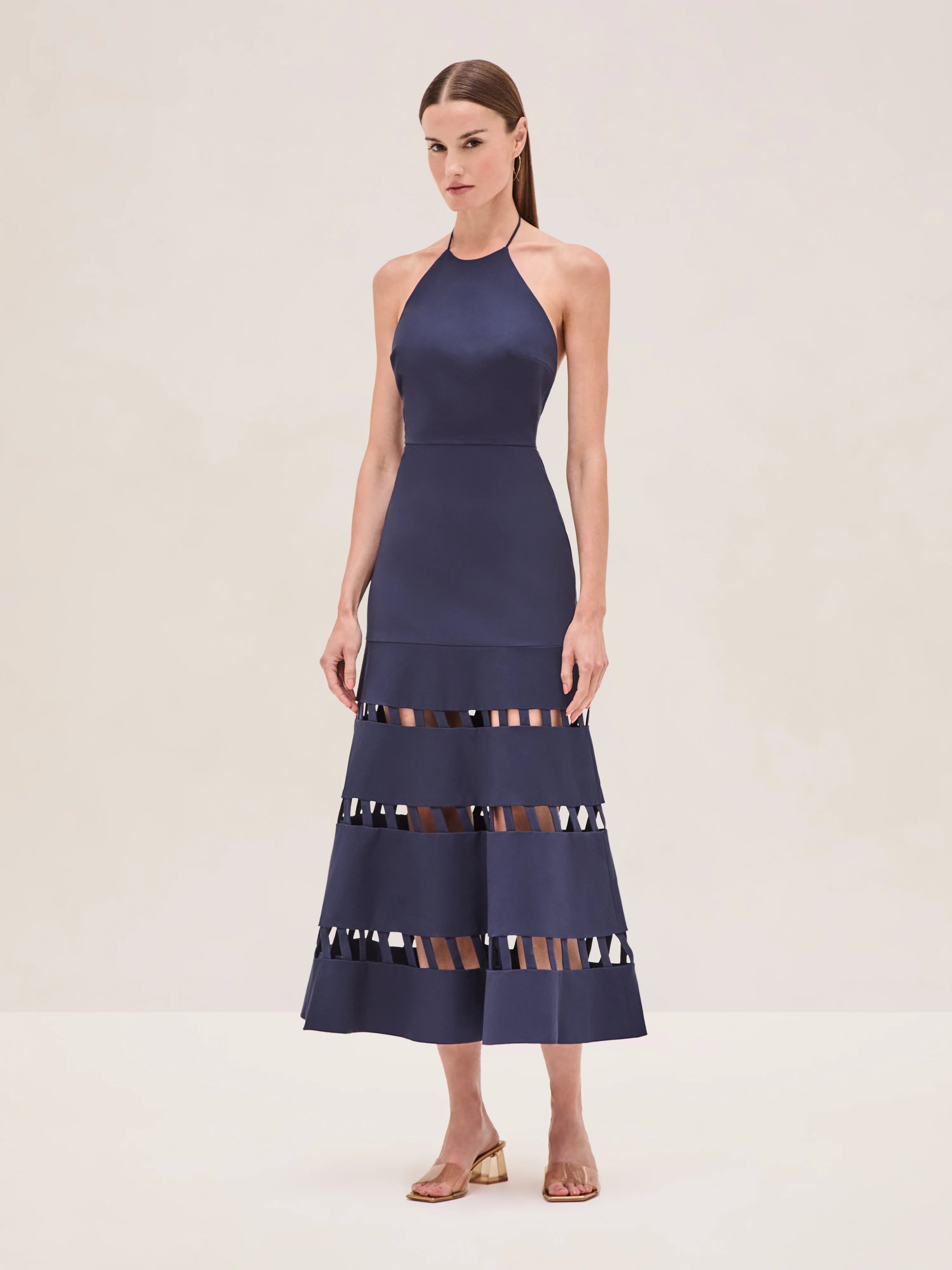 The Janessa Dress by Alexis combines classic comfort with modern detail through its breathable cotton fabric and halter neckline. Its midi length offers versatile styling options, while the distinctive cut-out ladder detailing adds an elegant touch of texture and visual interest, making it a refined choice for warm-weather occasions.